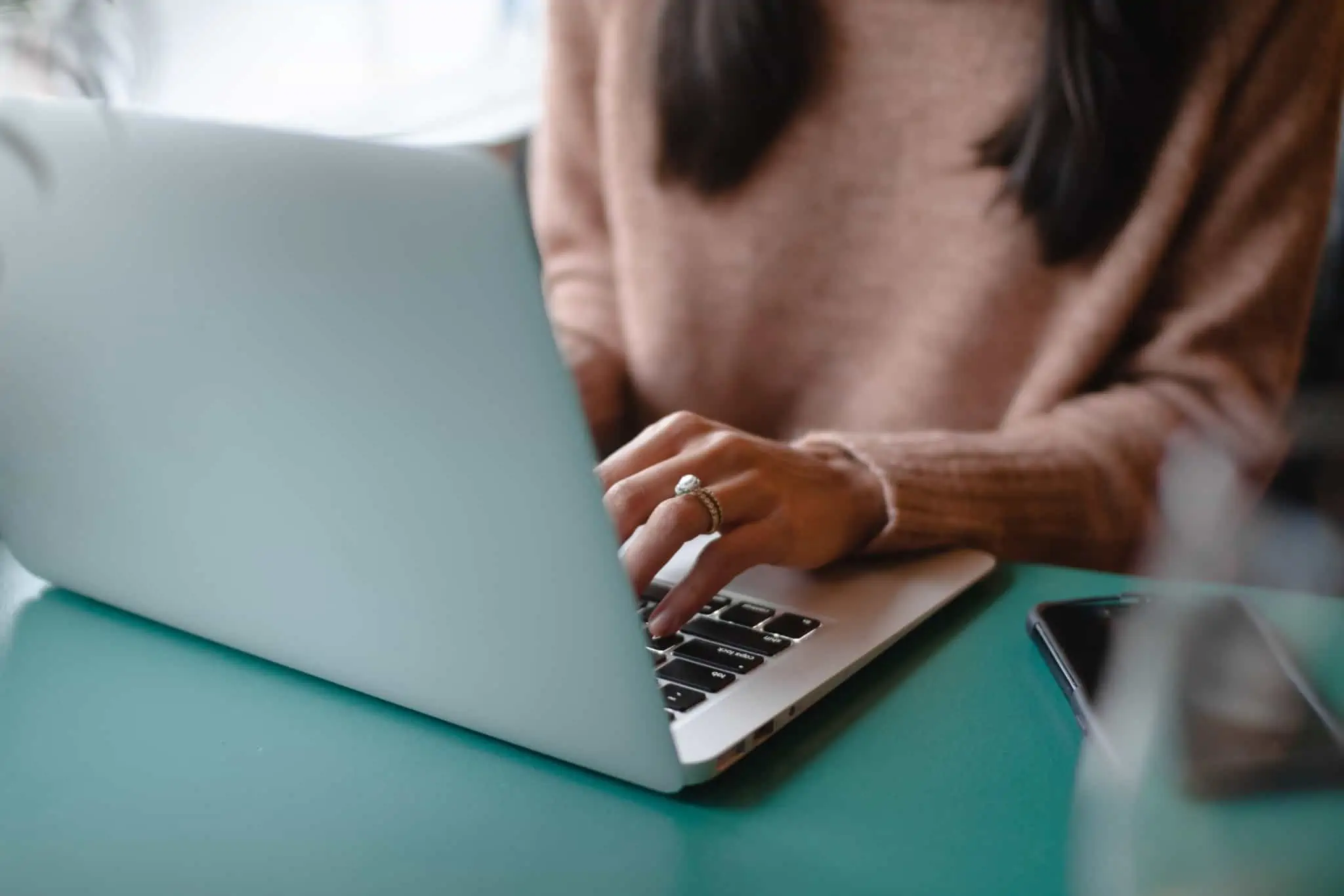 IRS Jovem: Quais os anexos a preencher? Jovem mulher sentada à mesa num computador a preencher IRS Jovem