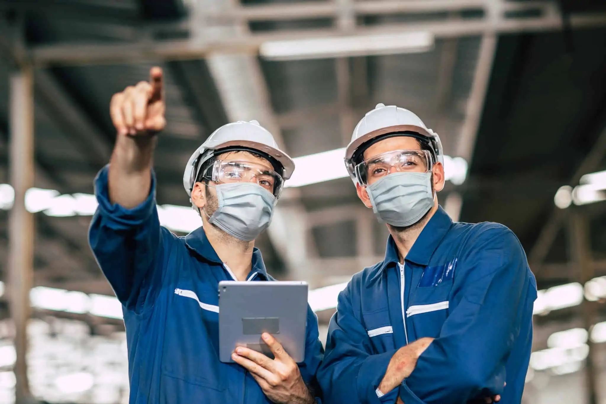 dois trabalhadores devidamente equipados a cumprir as normas de higiene e segurança no local de trabalho