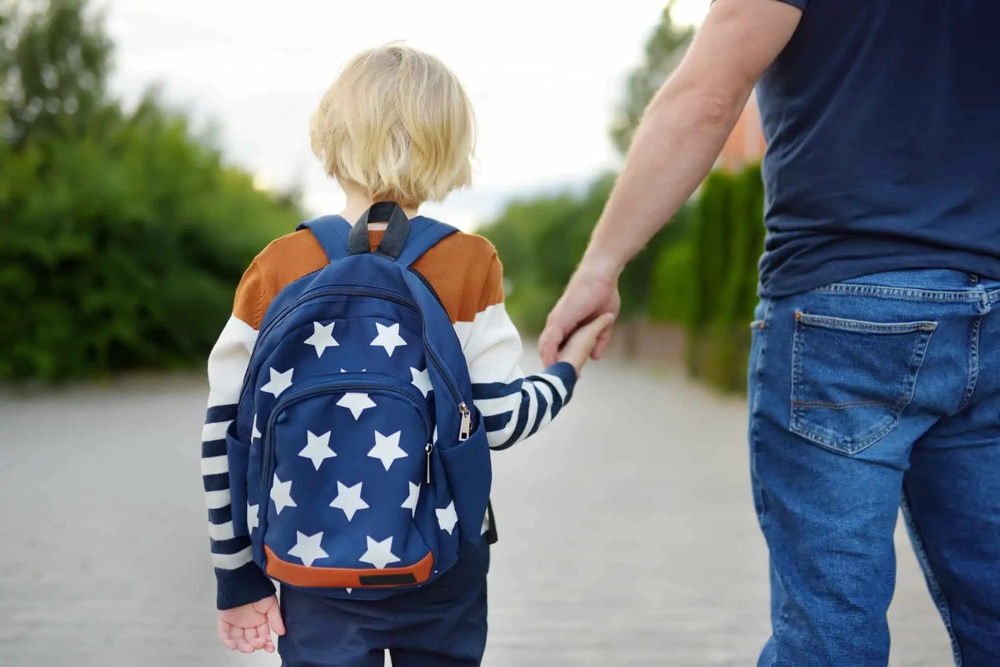 O seu filho vai para o primeiro ciclo? Saiba o que deve fazer criança com uma mochila de mão dada com o pai a ir na ida para o primeiro ciclo
