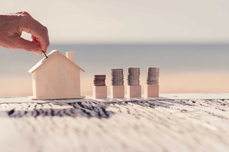 Casa de madeira e montes de moedas ao lado simbolizando rendimentos