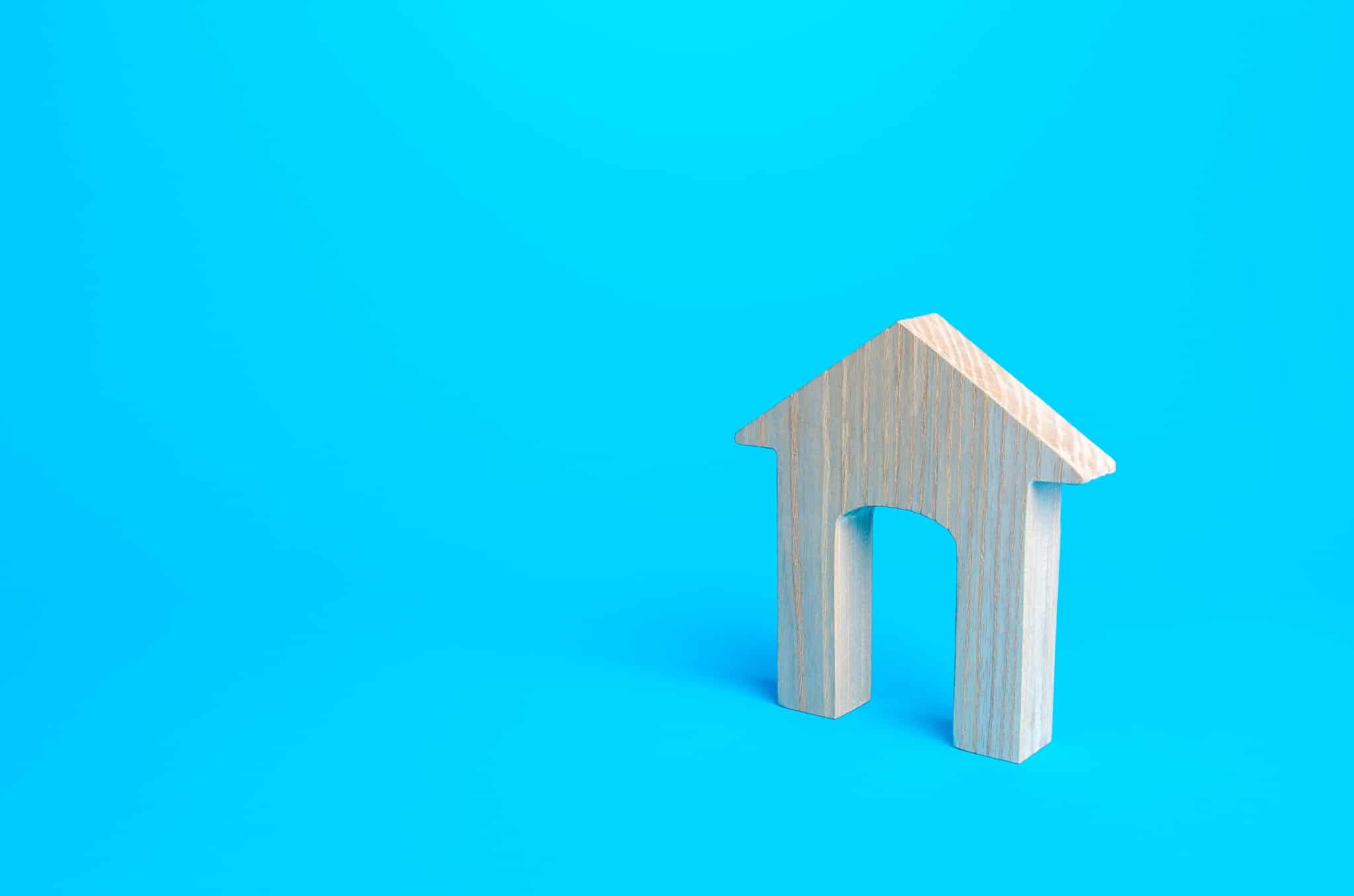 produção fotográfica minimalista que ilustra a compra de casa com um fundo azul e uma fachada de casa em madeira e sem porta
