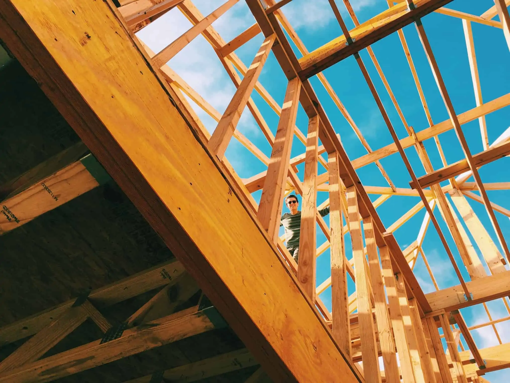 Comprar casa em construção: Vantagens, desvantagens e cuidados a ter jovem rapaz no zona do telhado ainda em construção ilustra o processo de comprar casa em construção