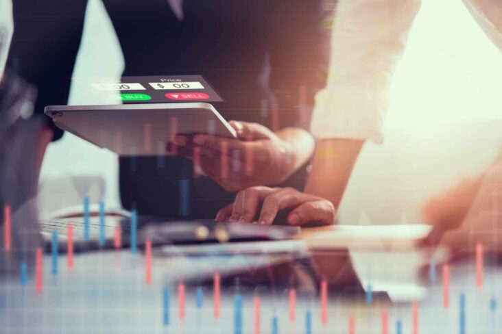 dois homens analisam evolução dos mercados financeiros , com gráficos e documentos digitais, estando ao serviço do regulador, ou seja, da CMVM