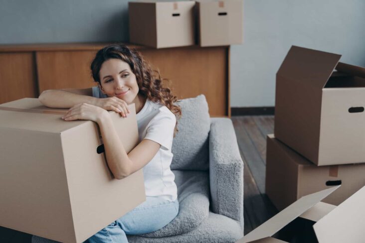 jovem com uma expressão de felicidade agarrada a uma caixa de mudanças, contente por ter decidido comprar a sua primeira casa