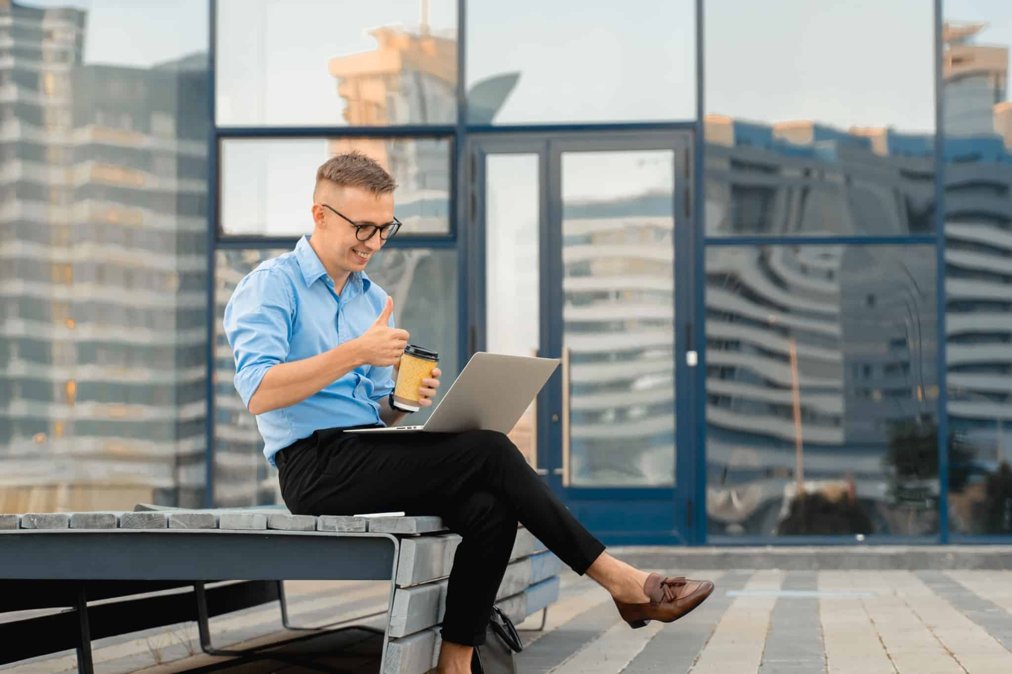 jovem rapaz, com um ar polido e profissional, mostra-se feliz ao fazer video chamada no computador, já atingiu os seus objetivos financeiros ou seja, independência