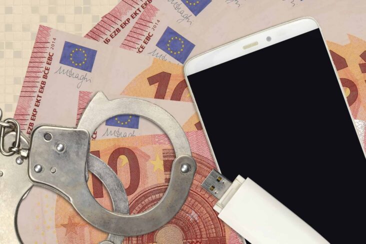 Smishing ilustrado com notas de euros sobre as quais foram colocadas umas algumas, uma pen com dados e um telemóvel, o equipamento veículo para esta fraude feita via SMS
