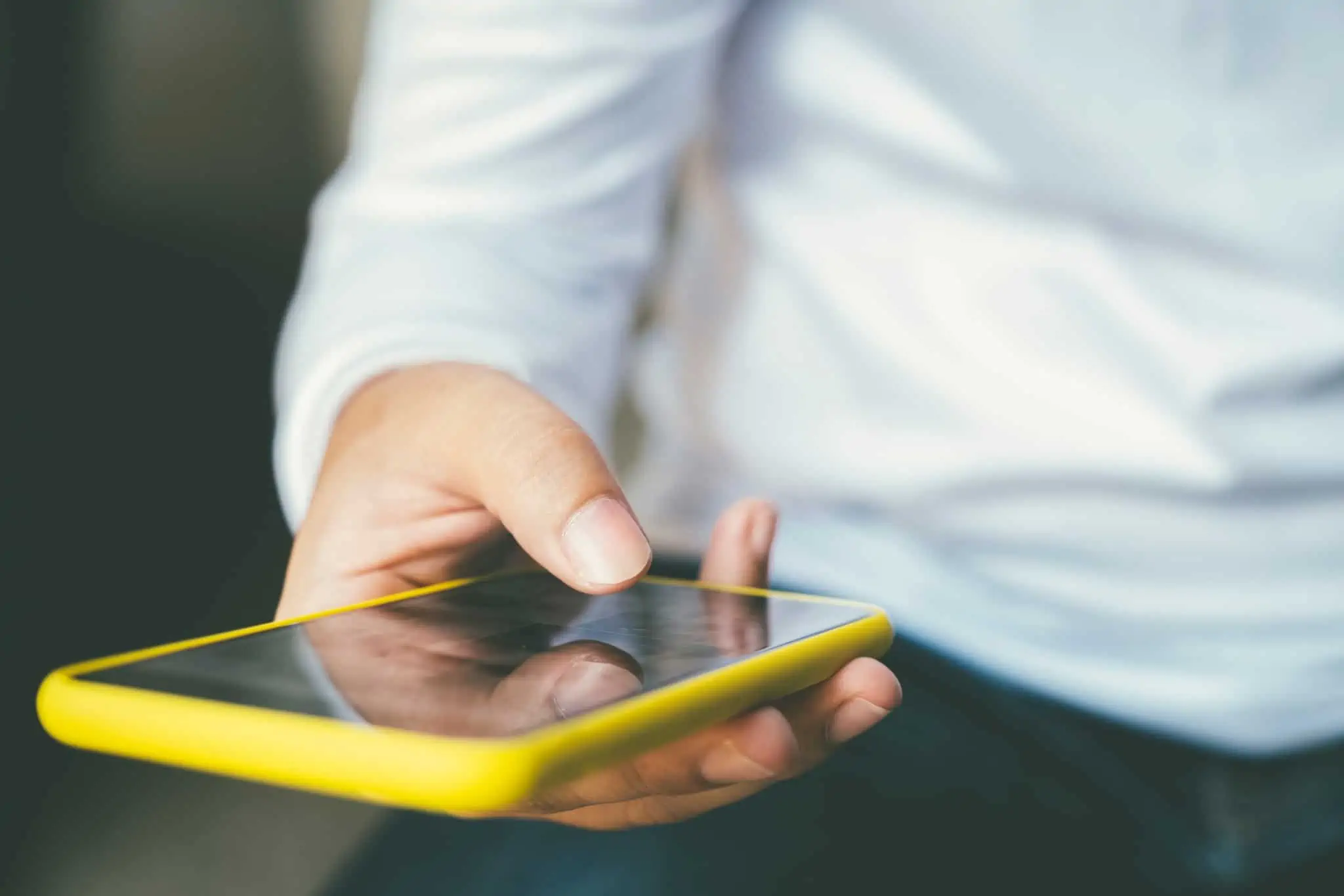 mãos de um jovem rapaz seguram telemóvel enquanto consulta 4 sites para comprar telemóveis baratos