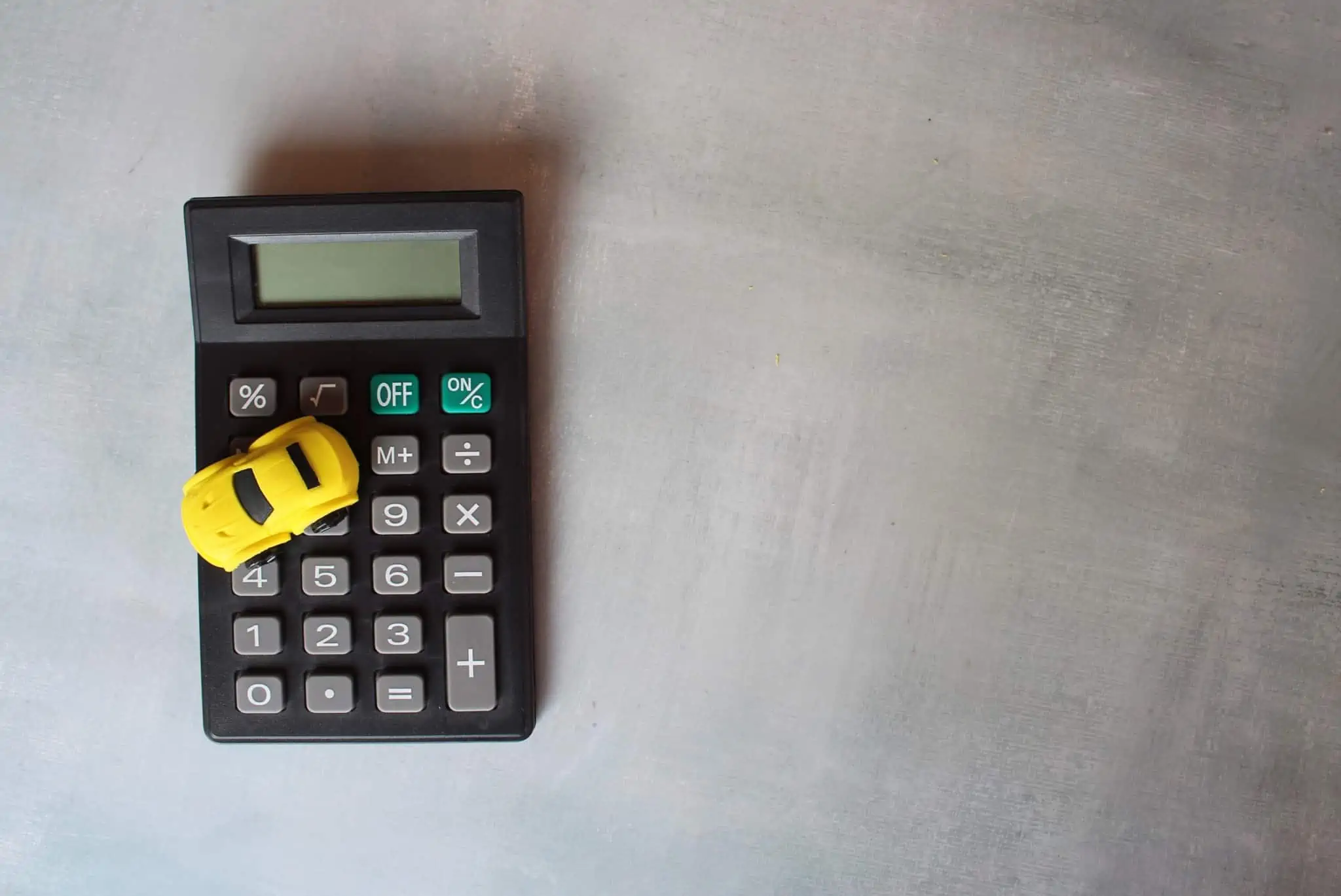 Tenho um crédito automóvel. Consigo um crédito para comprar uma casa? um carrinho em cima de uma calculadora a ilustrar se é possível obter um crédito para comprar casa quando se tem um crédito automóvel