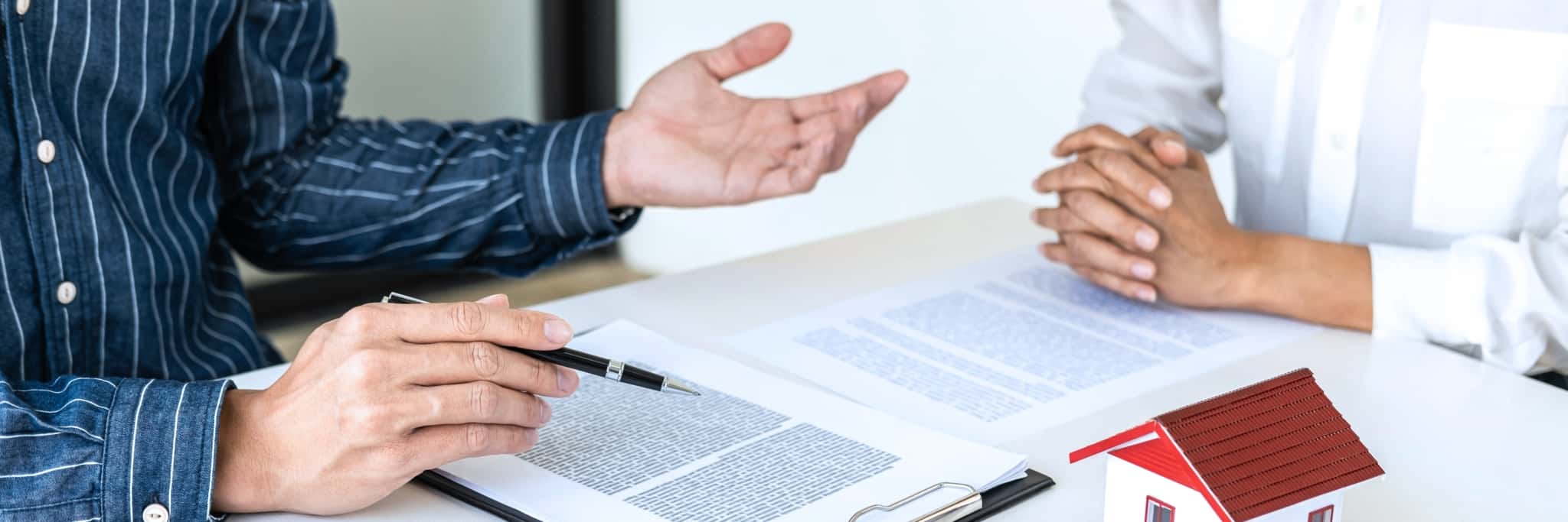 Mãos de homens sobre uma mesa com papéis simbolizando assinatura de crédito habitação