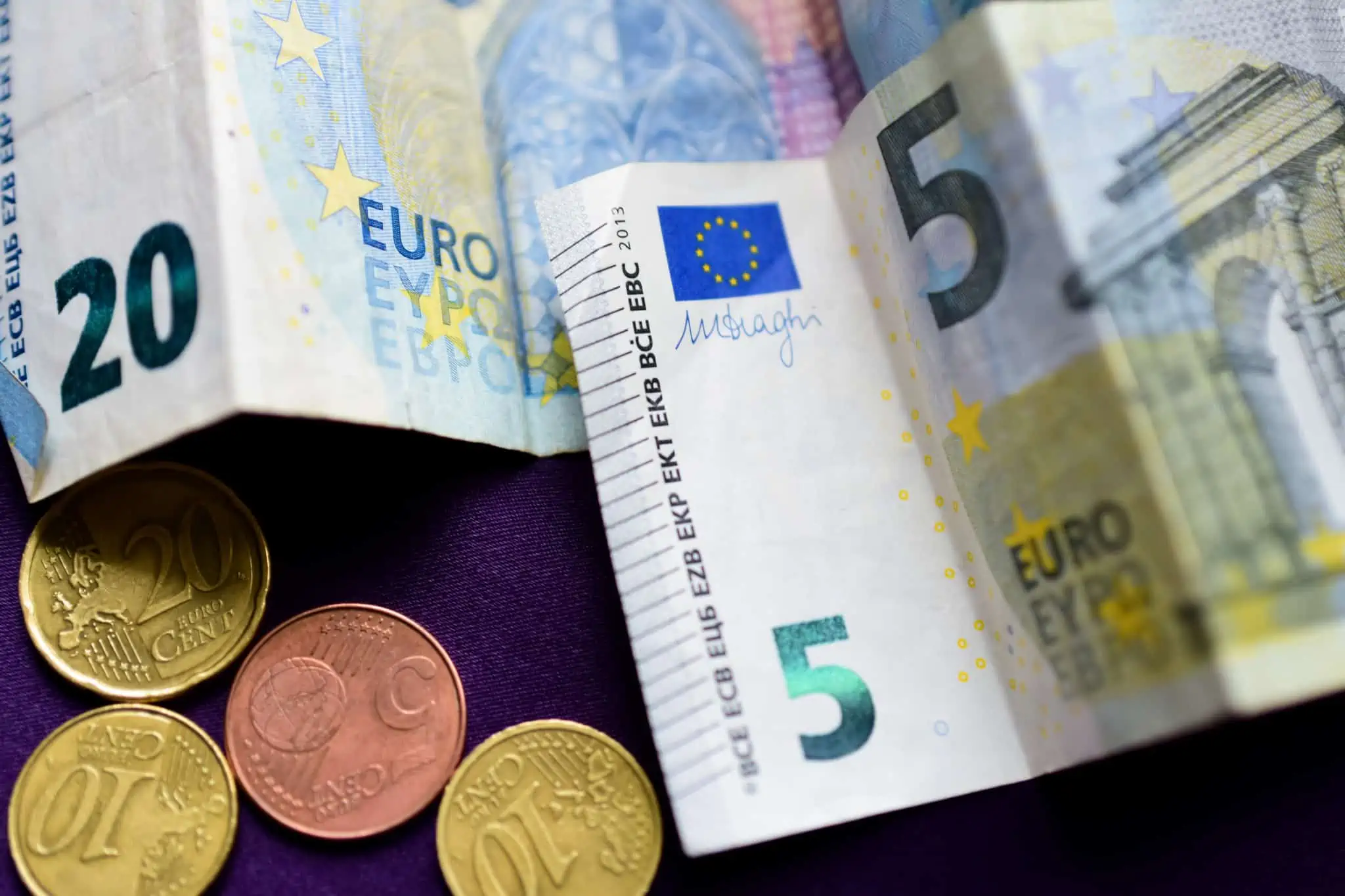 Como consultar os pagamentos da Segurança Social notas e moedas de euro em cima de uma mesa preparados para serem depositados numa conta poupança