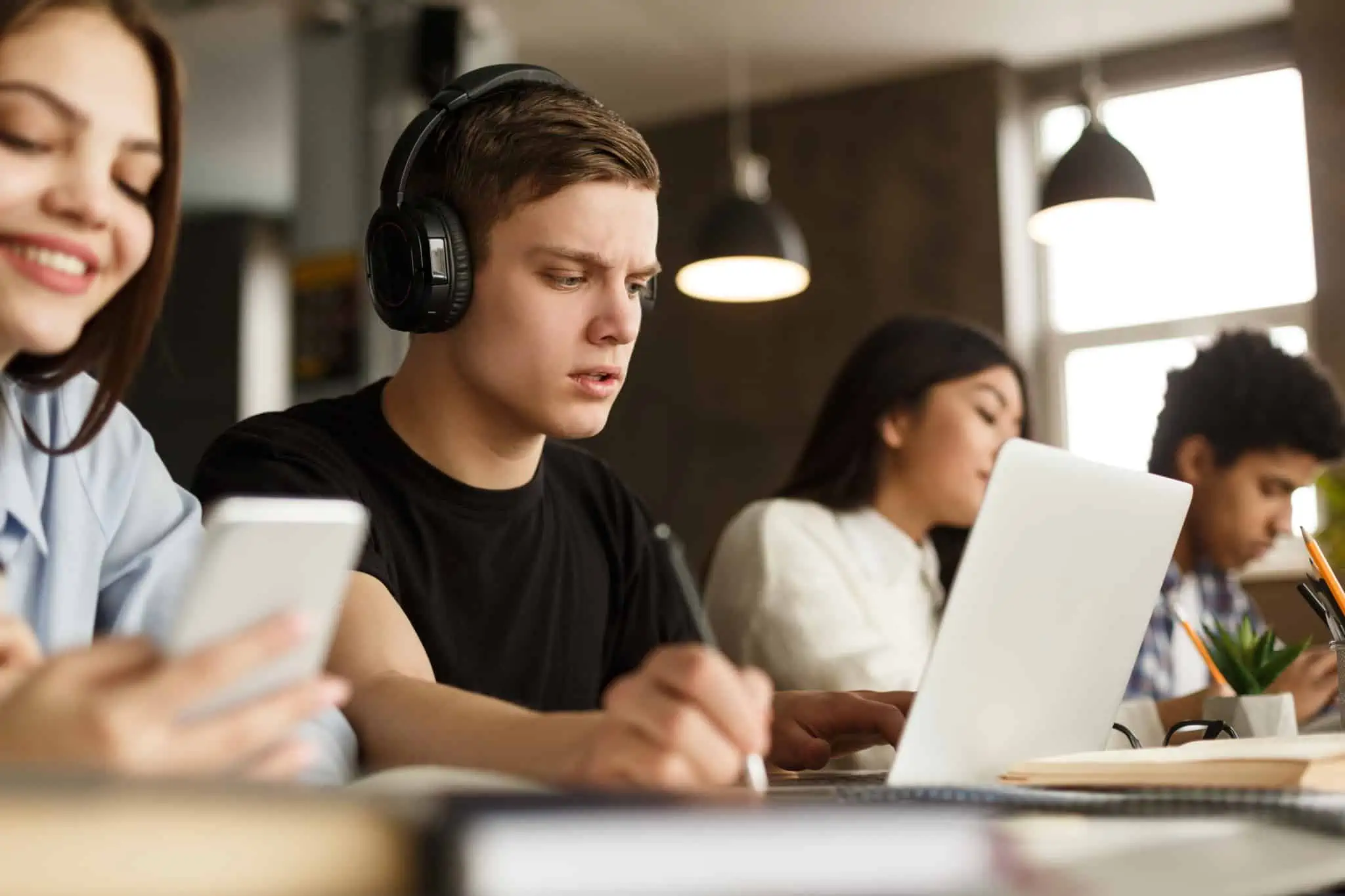 Quanto custa um mestrado e uma pós-graduação em Portugal? Alunos sentados numa secretária com computadores e telemóveis à frente numa sala de mestrado/pós-graduação
