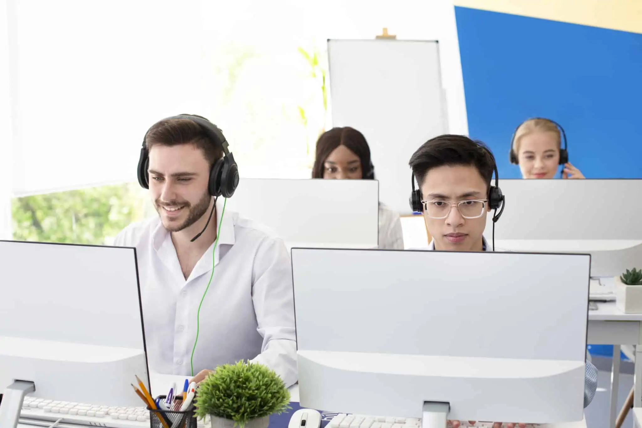 Linhas de apoio ao cliente: O que muda com as novas regras grupo de quatro jovens, rapazes e raparigas, a atender em linhas de apoio ao cliente