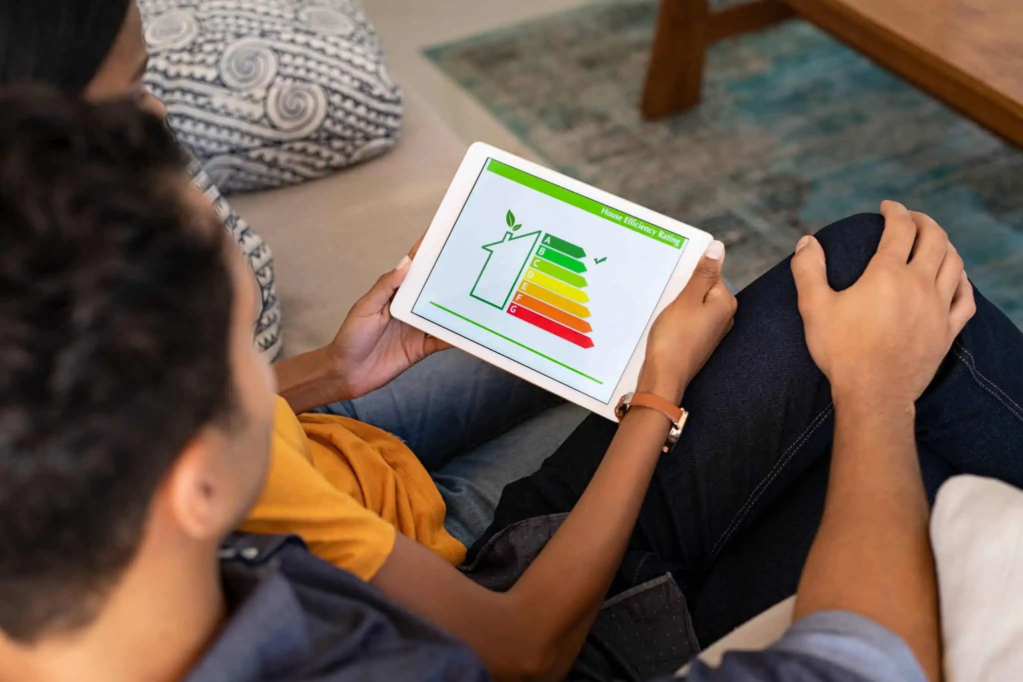 Energia: 7 formas de tornar a sua casa mais eficiente Casal sentado de costas a observar ipad com níveis de casa eficientemente energética