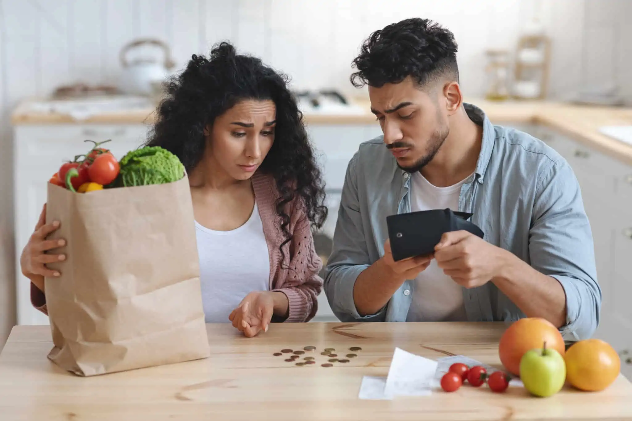 10 apoios para famílias carenciadas casal de jovens faz contas aos trocos, carregando um saco de compras, remetendo para as famílias carenciadas