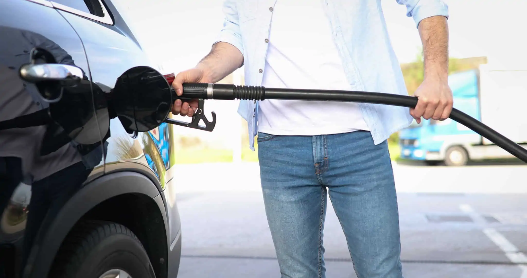 Combustível simples ou aditivado: Qual compensa mais? jovem homem a abastecer o carro na bomba de gasolina, optando entre combustível aditivado ou simples, de forma a conseguir poupar em tempos de grandes aumentos dos preços
