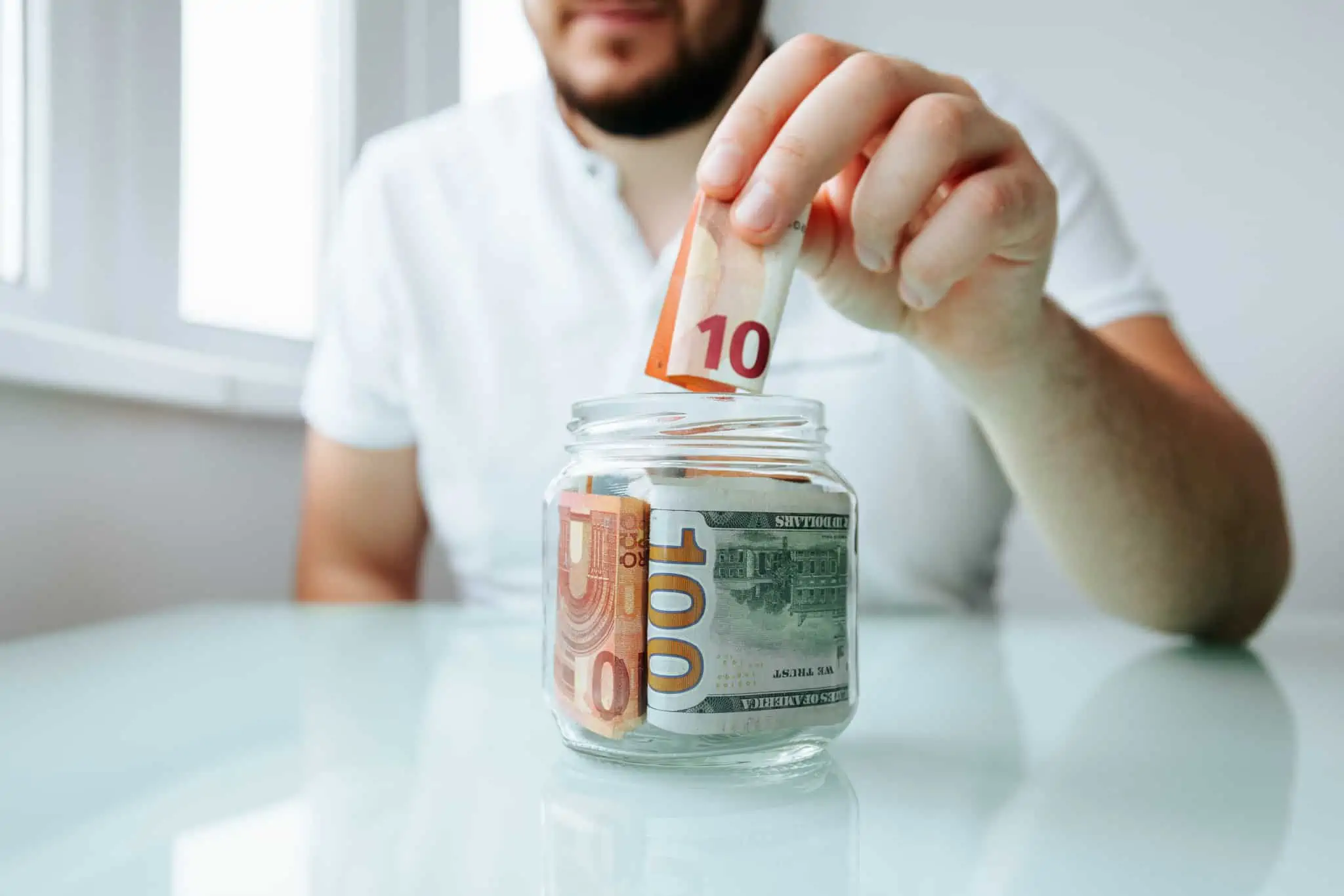Dar uma gratificação: O que significa e quais as regras em vigor jovem rapaz reúne as suas gorjetas, num frasco de vidro, reunindo tudo o que foi gratificação