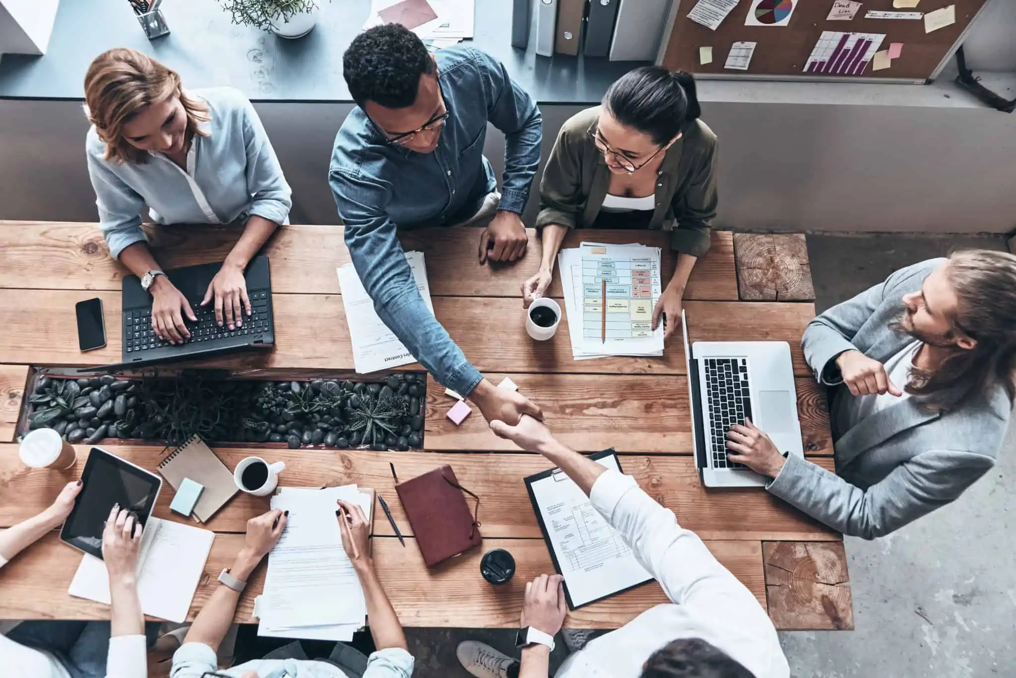 Várias pessoas sentadas a uma mesa, numa reunião de trabalho, onde é assinado um acordo