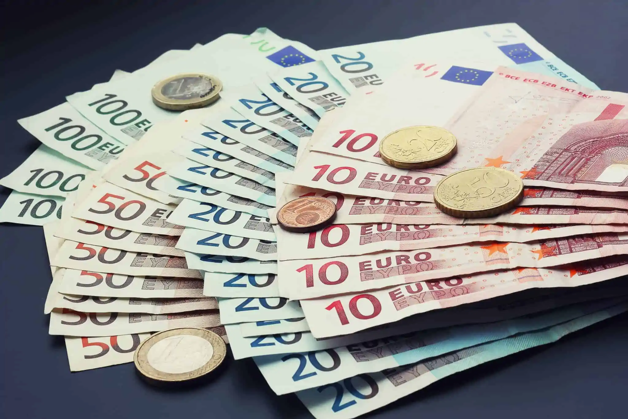 Desvalorização do euro: Qual o impacto nas suas finanças pessoais? molho de notas e algumas moedas de Euro ilustram a possível desvalorização do euro e o seu impacto