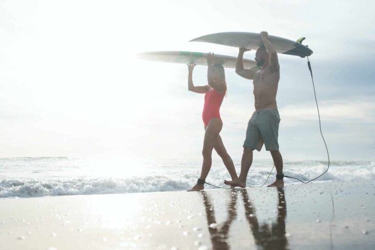 Jovens na praia a carregar pranchas de surf