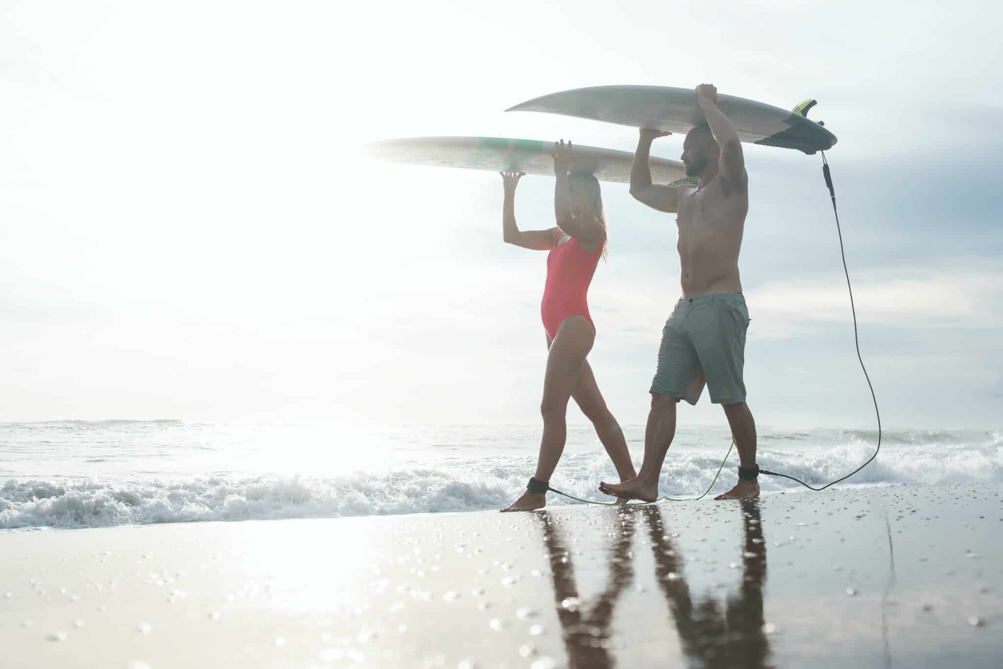 Jovens na praia a carregar pranchas de surf