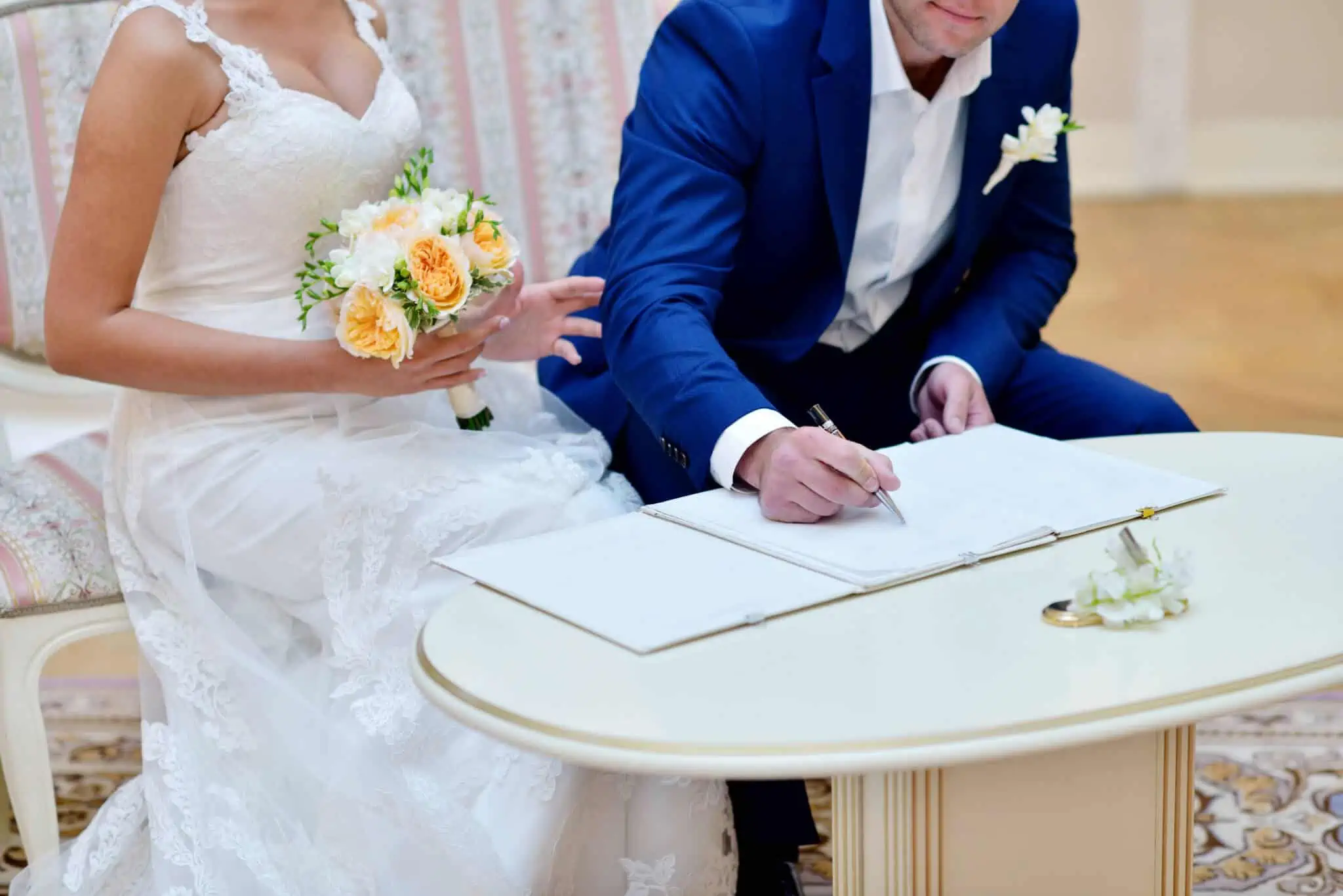 Quanto custa um casamento? E como posso financiar? Casal vestido de noivos a assinar papéis de casamento