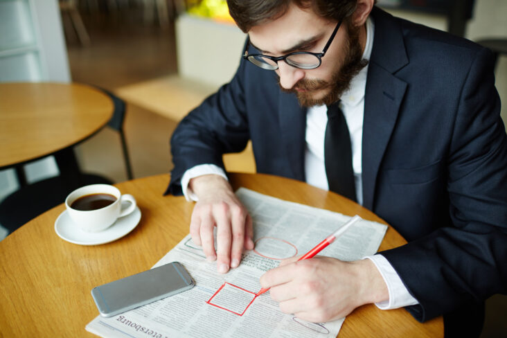 Homem a ler a secção de anúncios de emprego no jornal