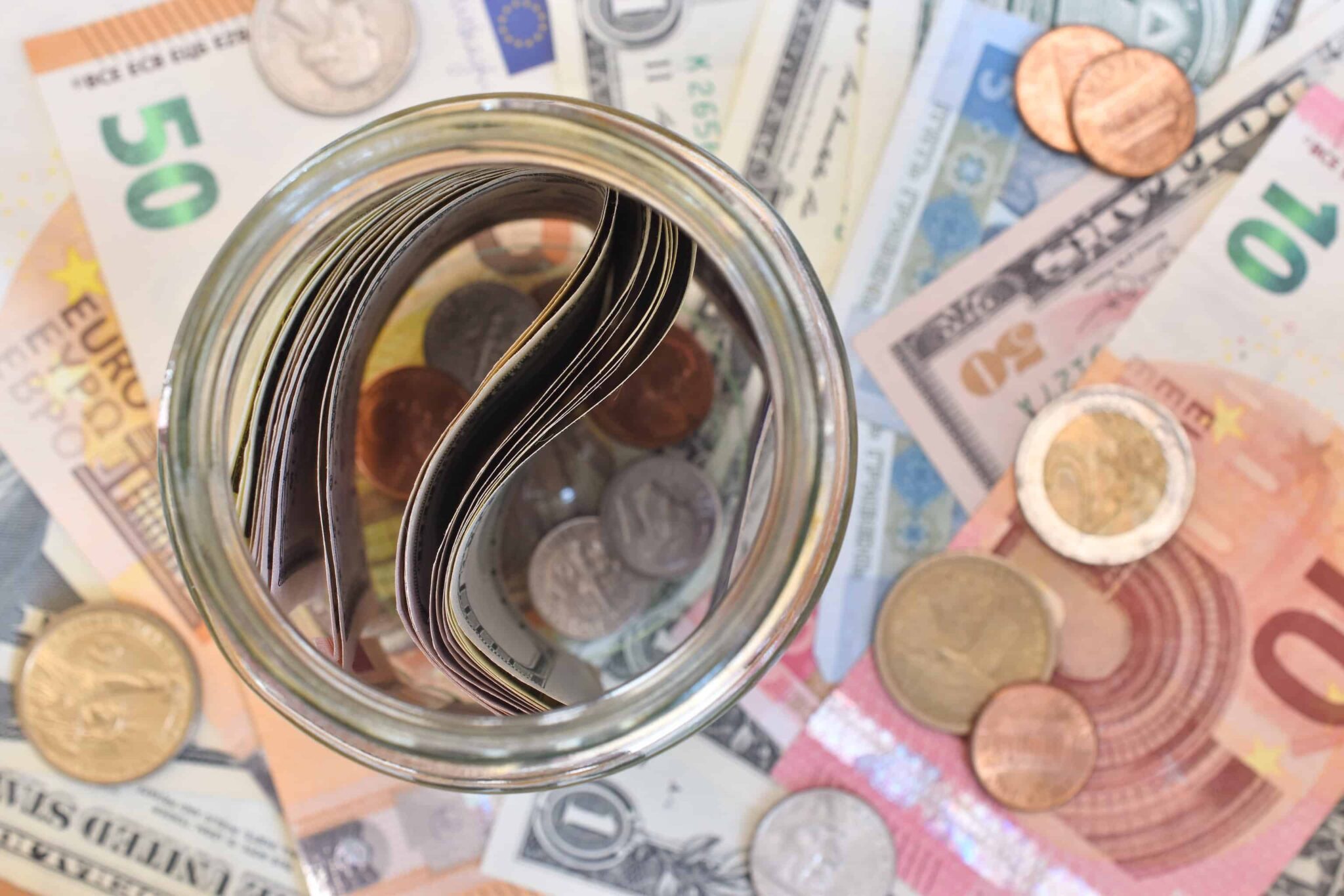 Como garantir deduções de IRS? Frasco com notas dentro e notas e euros por baixo simbolizando deduções de IRS