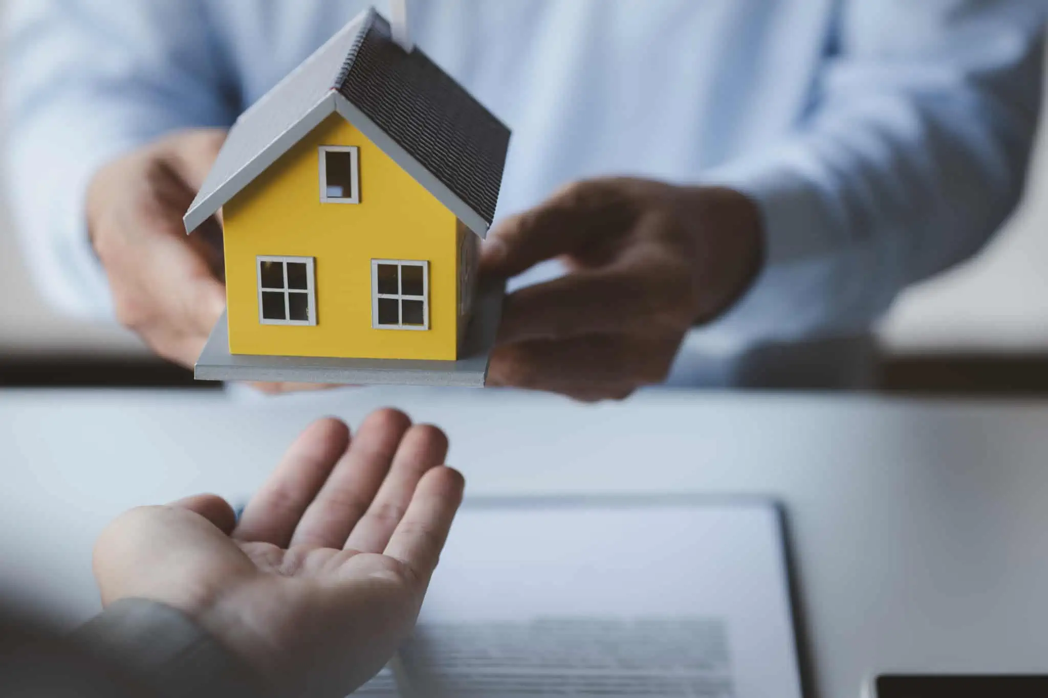 Vou comprar casa, quanto tempo demora fazer um crédito? duas pessoas a passar uma casa para a outra a representar o crédito multiopções com reforço hipotecário