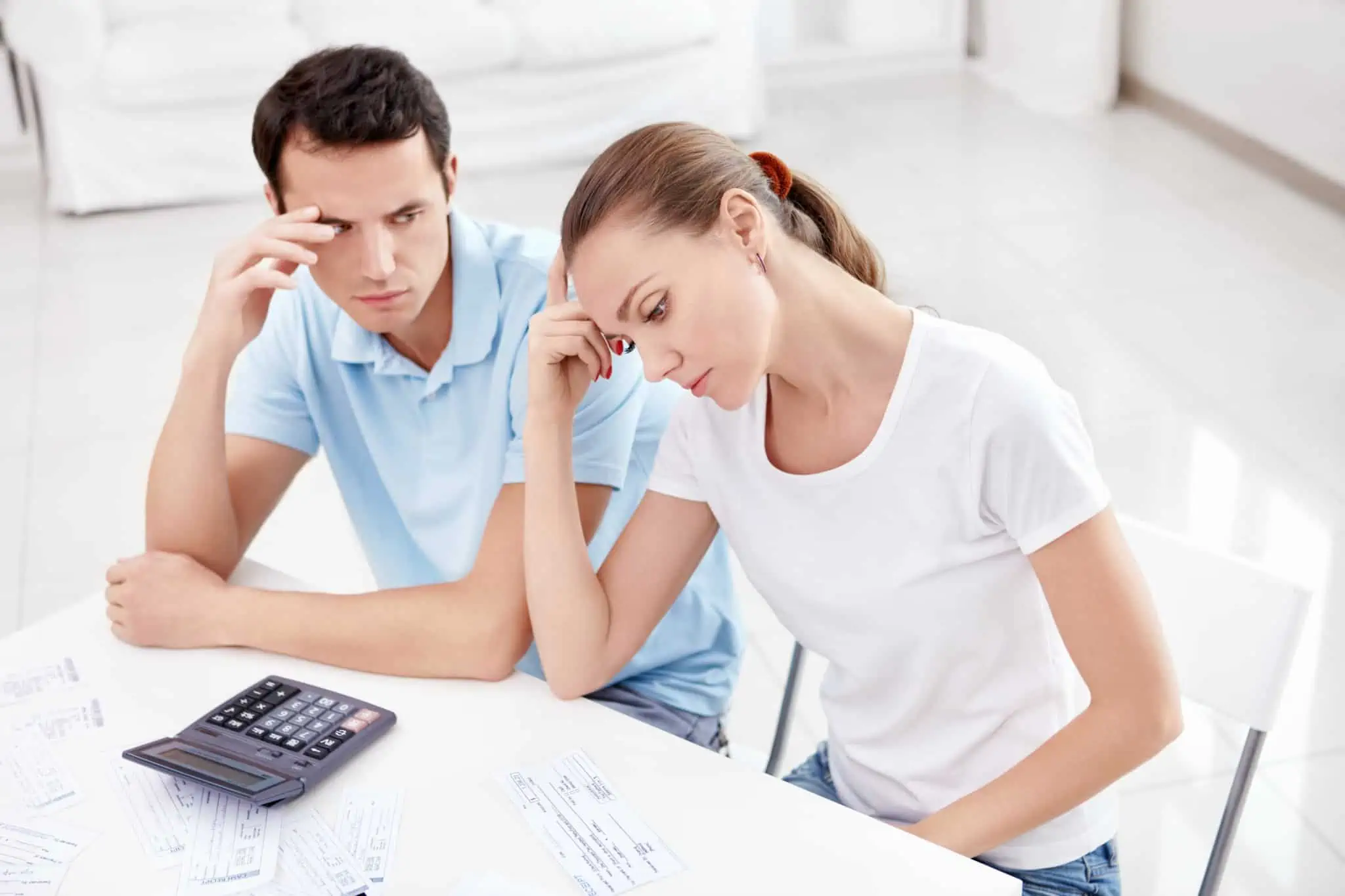 Denúncia às Finanças: Quem pode fazer, quando e como? Jovem casal com o rosto de grande preocupaçao analisa documentos para decidir avançar com denúncia às Finanças