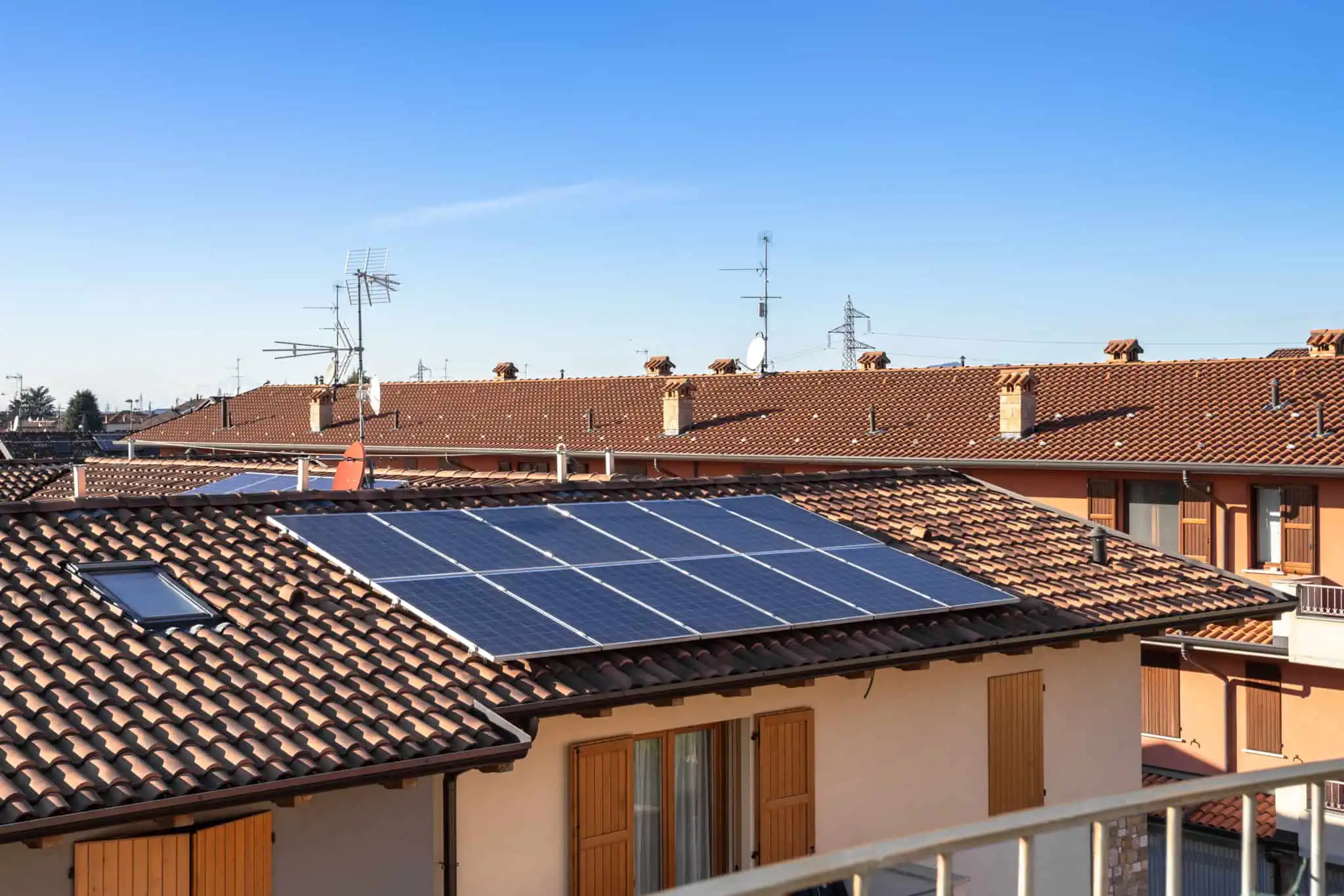 Painéis solares: Quando vale a pena instalar? conjunto de casas, moradias, com uma delas de telhado vermelho onde estão instalados painéis solares