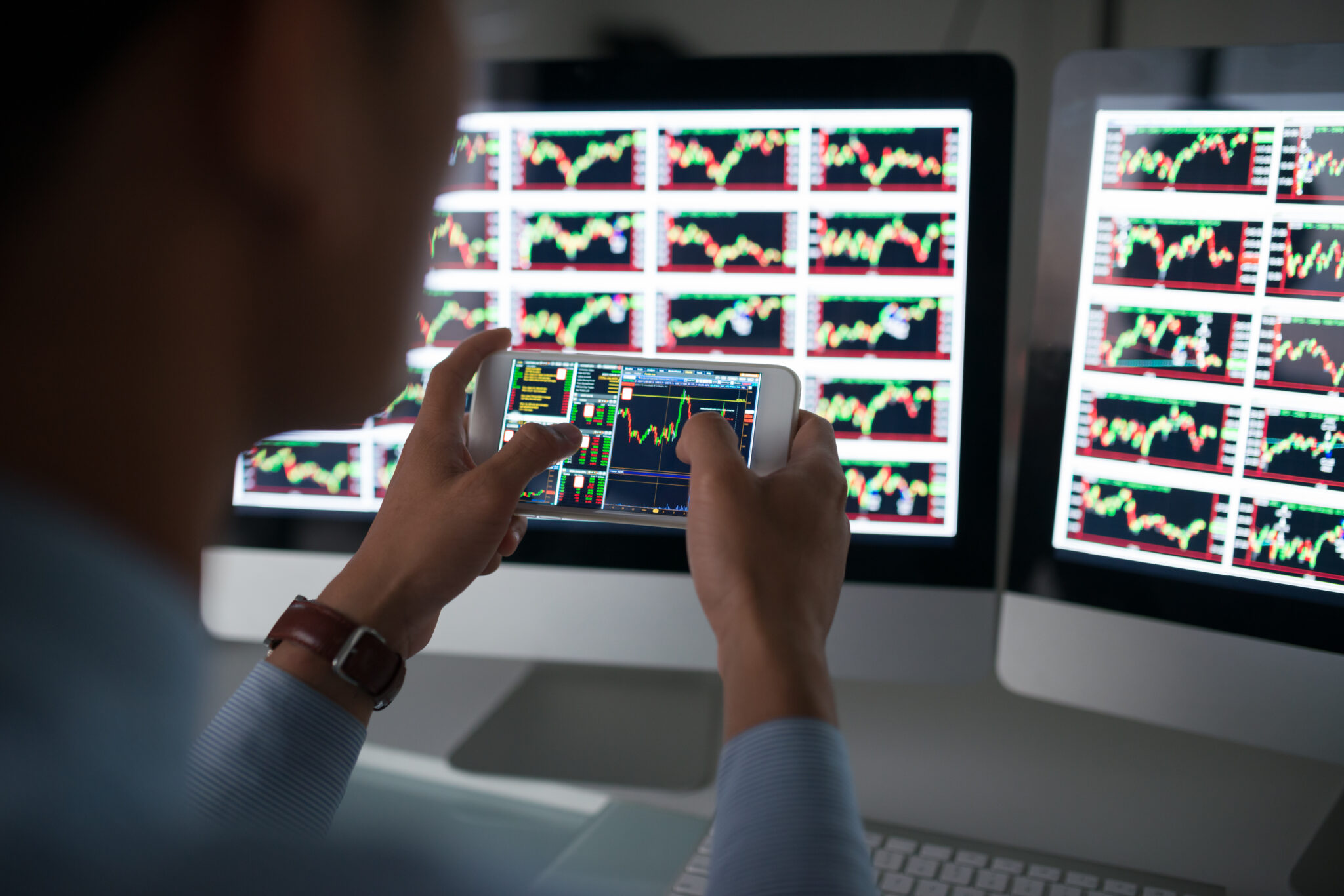 Os temas e tendências que vão dominar os mercados em 2023 Investidor a analisar gráficos dos mercados no computador e smartphone