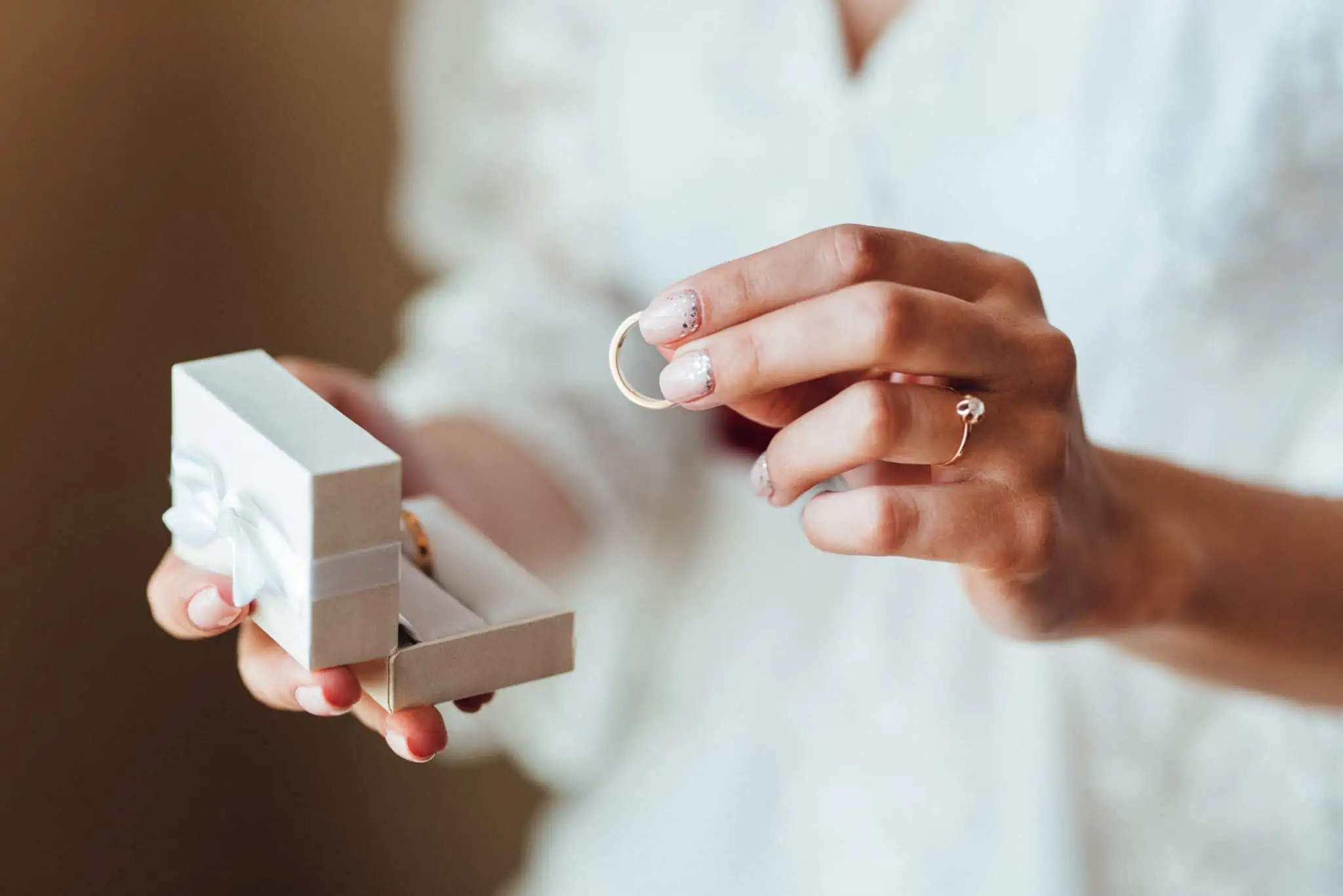 Quanto custa um casamento civil? Mãos de mulher a segurar caixa de alianças e aliança de casamento civil