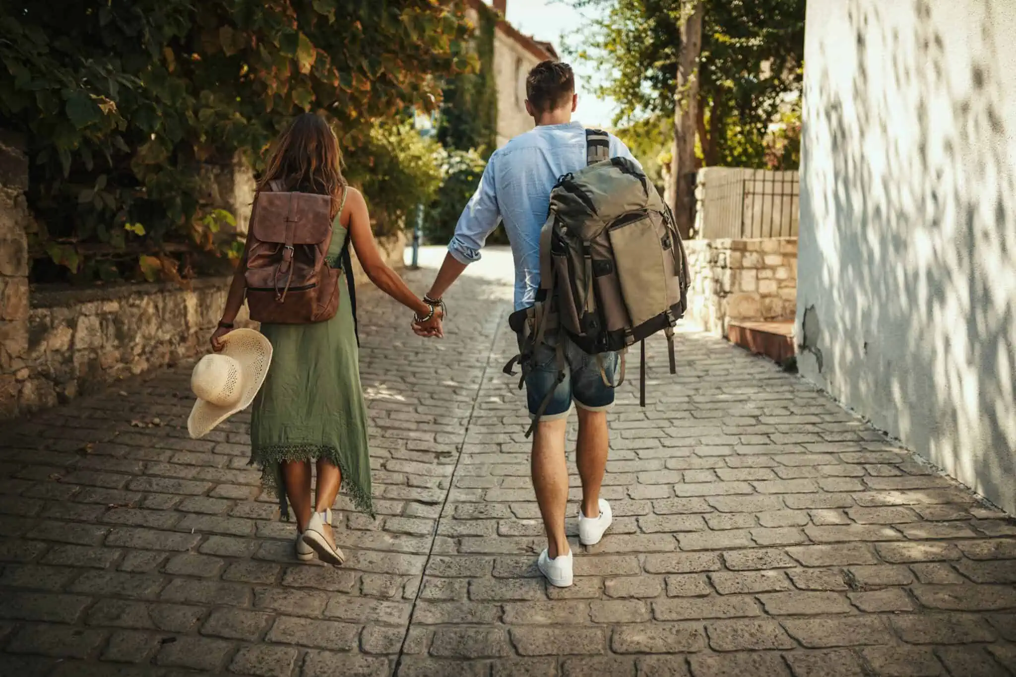 Investir em alojamento local: Que tributação e rentabilidade esperar? um casal de jovens turistas a caminhar pelas ruas antigas de uma cidade, a procurar um alojamento local