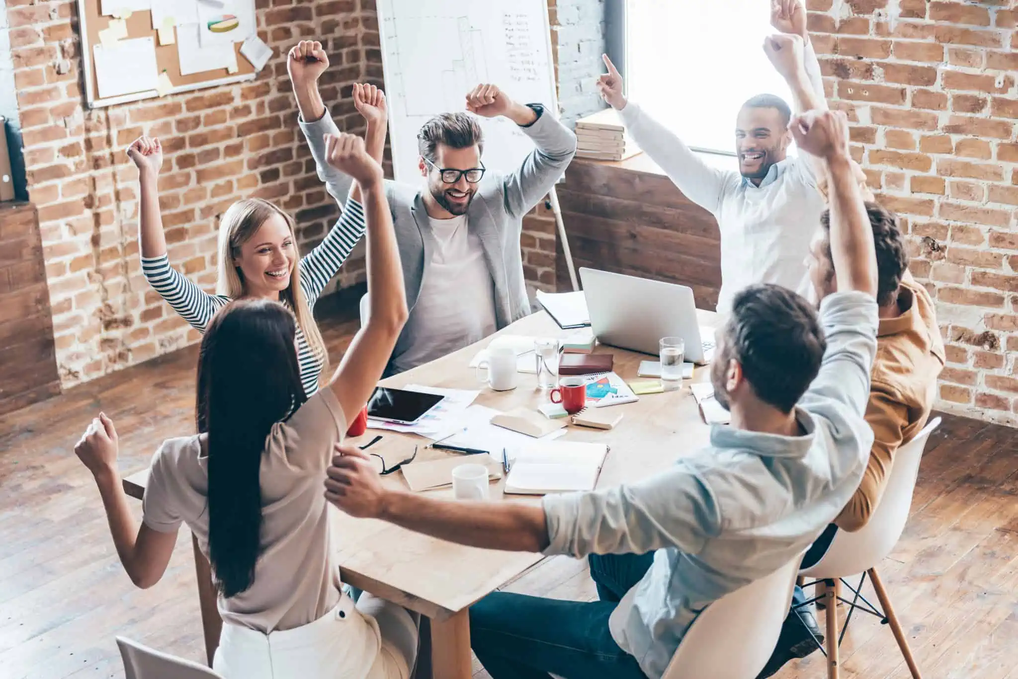 Realização profissional: O que podem fazer por si estes 11 livros grupo de jovens trabalhadores, a festejar , de braços no ar, em torno de uma mesa no escritório, a celebrarem a sua realização profissional