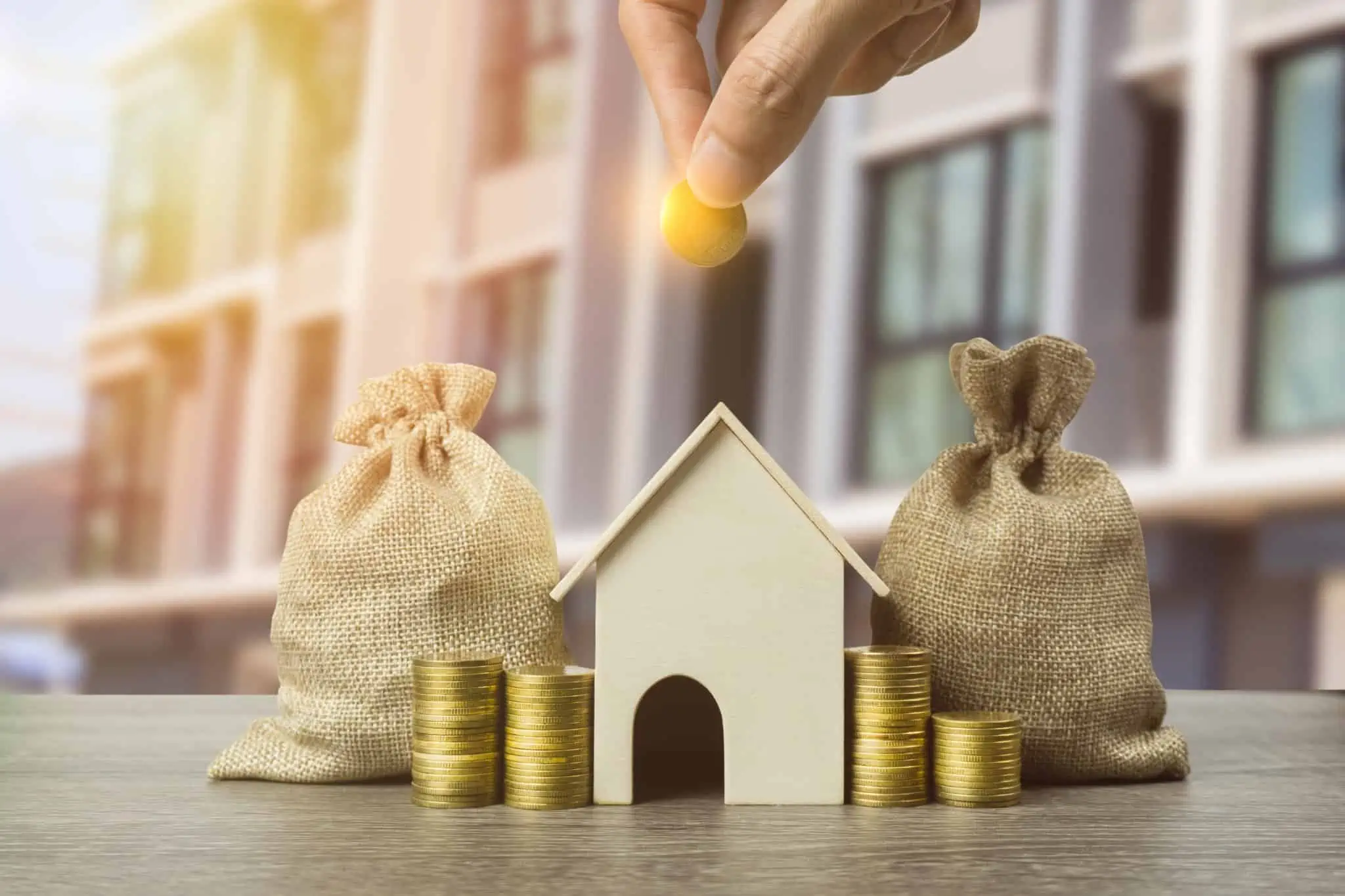 Crédito habitação: Quais os rendimentos considerados pelo banco imagem de uma casa com sacos e moedas a ilustrar quais os rendimentos considerados pelos bancos no crédito habitação