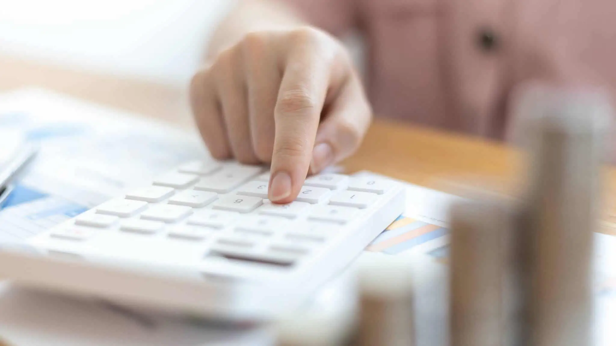 Como funciona o IRS sobre o investimento mobiliário? Mão a mexer em calculadora simbolizando contas sobre declaração de investimento mobiliário no IRS