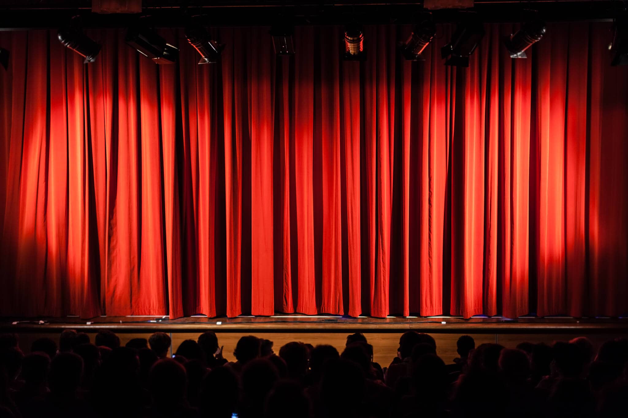Espetáculos culturais: Mantenha-se informado e poupe nos bilhetes foco de luz apontado para um cortinado vermelho sob um palco que recebe espectáculos culturais