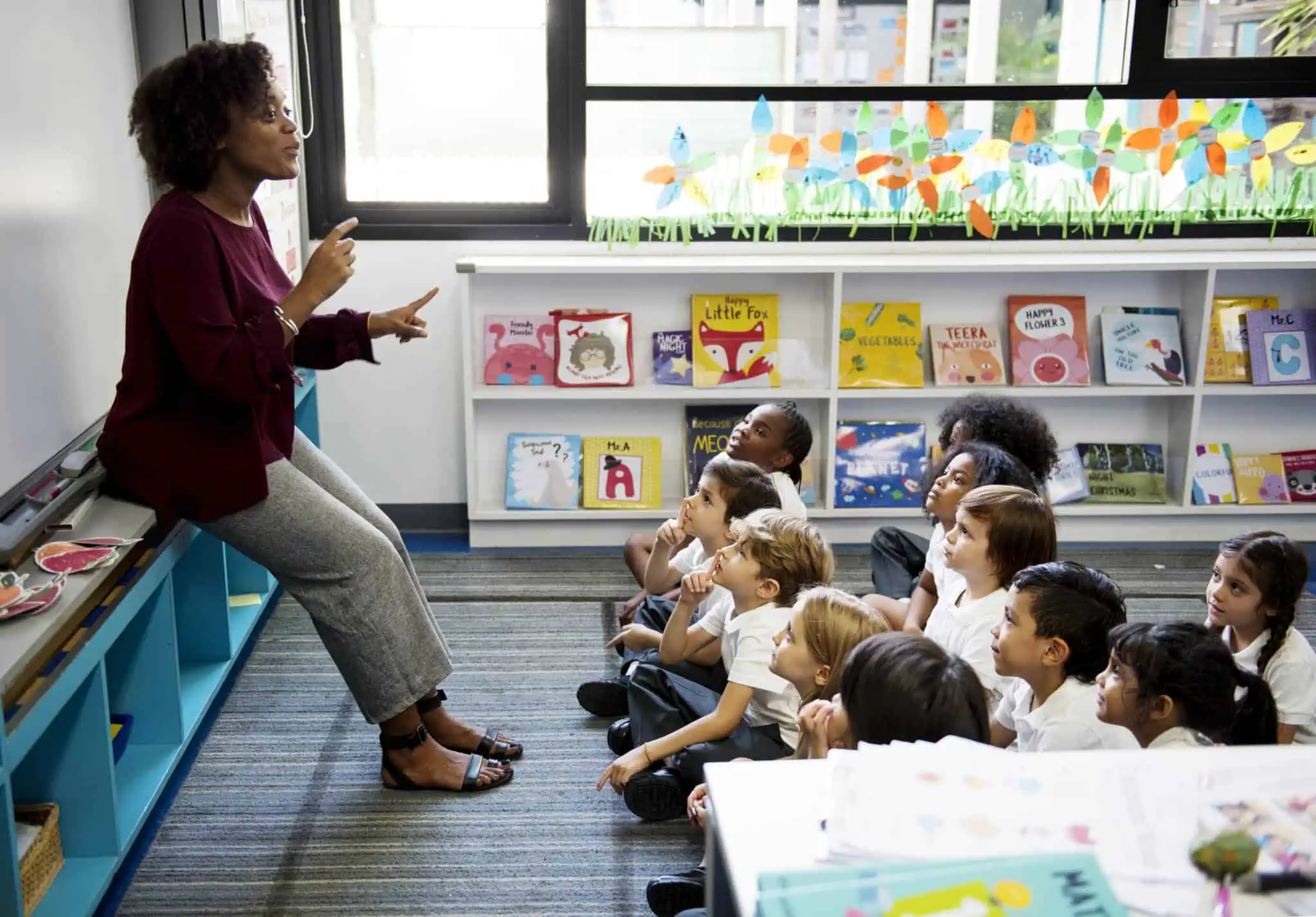 Necessidades educativas especiais? Conheça os apoios escolares na sala de infantário um grupo de crianças escutam com atenção a professora especializada em necessidades educativas especiais