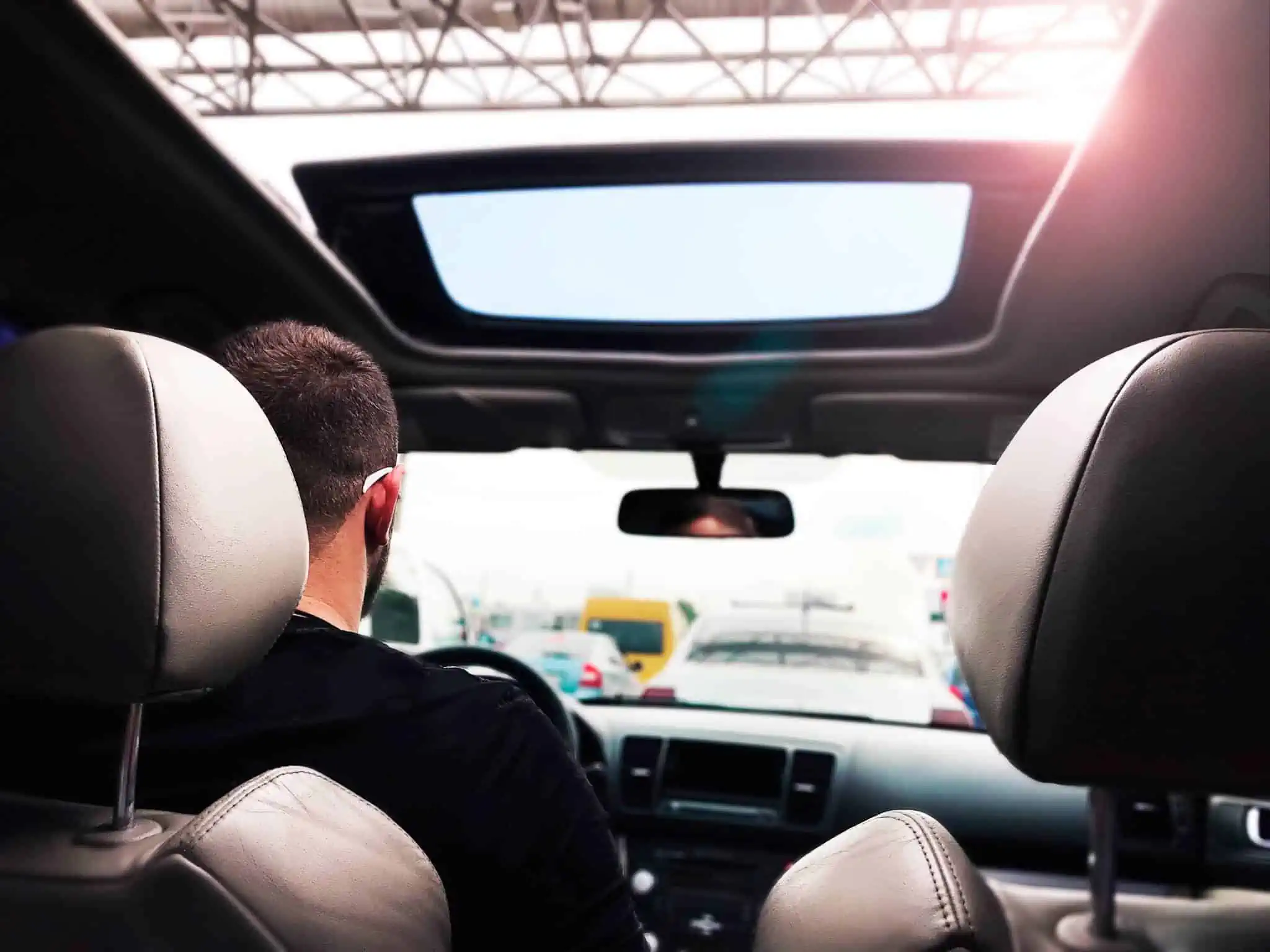 Dístico do seguro: Já não é obrigatório afixar no vidro do carro jovem rapaz a conduzir , com perpsetiva da frente vendo-se o vidro da frente carro, no qual o dístico do seguro já não é obrigatório