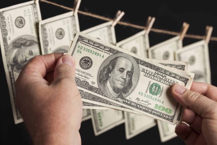 Homem a pendurar notas de dólar numa corda