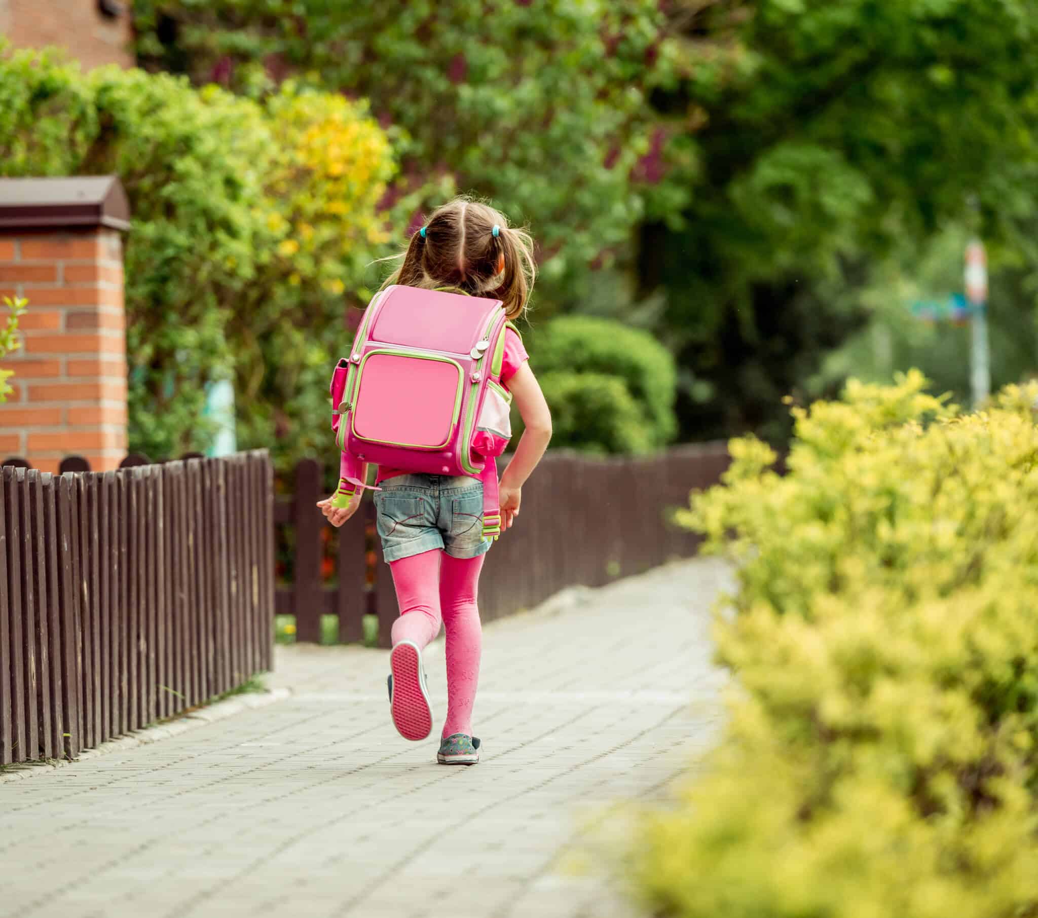 Matrículas: Que passos dar até ao quinto ano do ensino básico menina, a iniciar o percurso escolar, vai de mochila rosa às costas pela rua, depois de os pais terem feito as matrículas