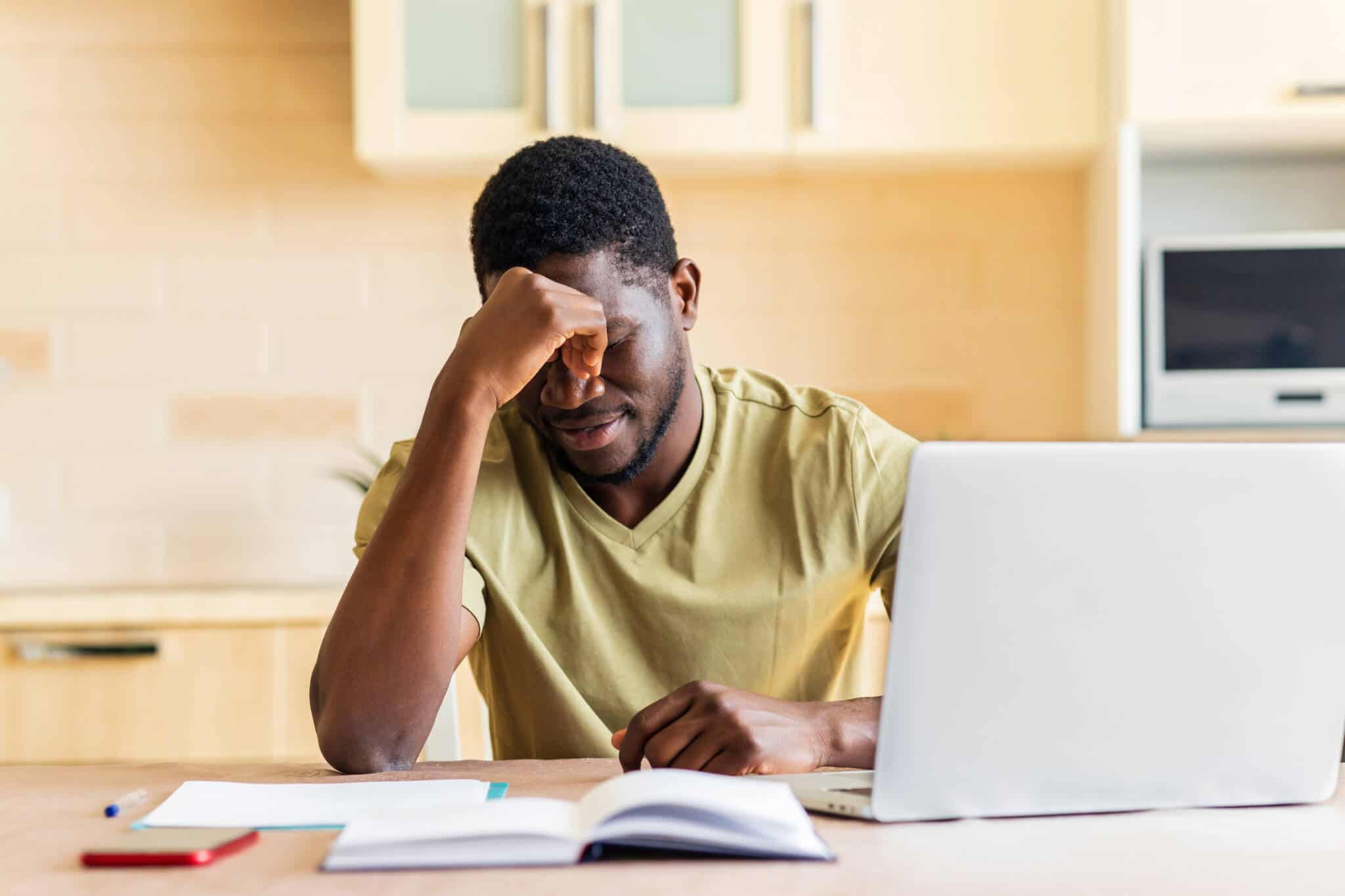 Homem em frente ao computador de cabeça baixa a ilustrar como o planeamento pode reduzir a ansiedade financeira