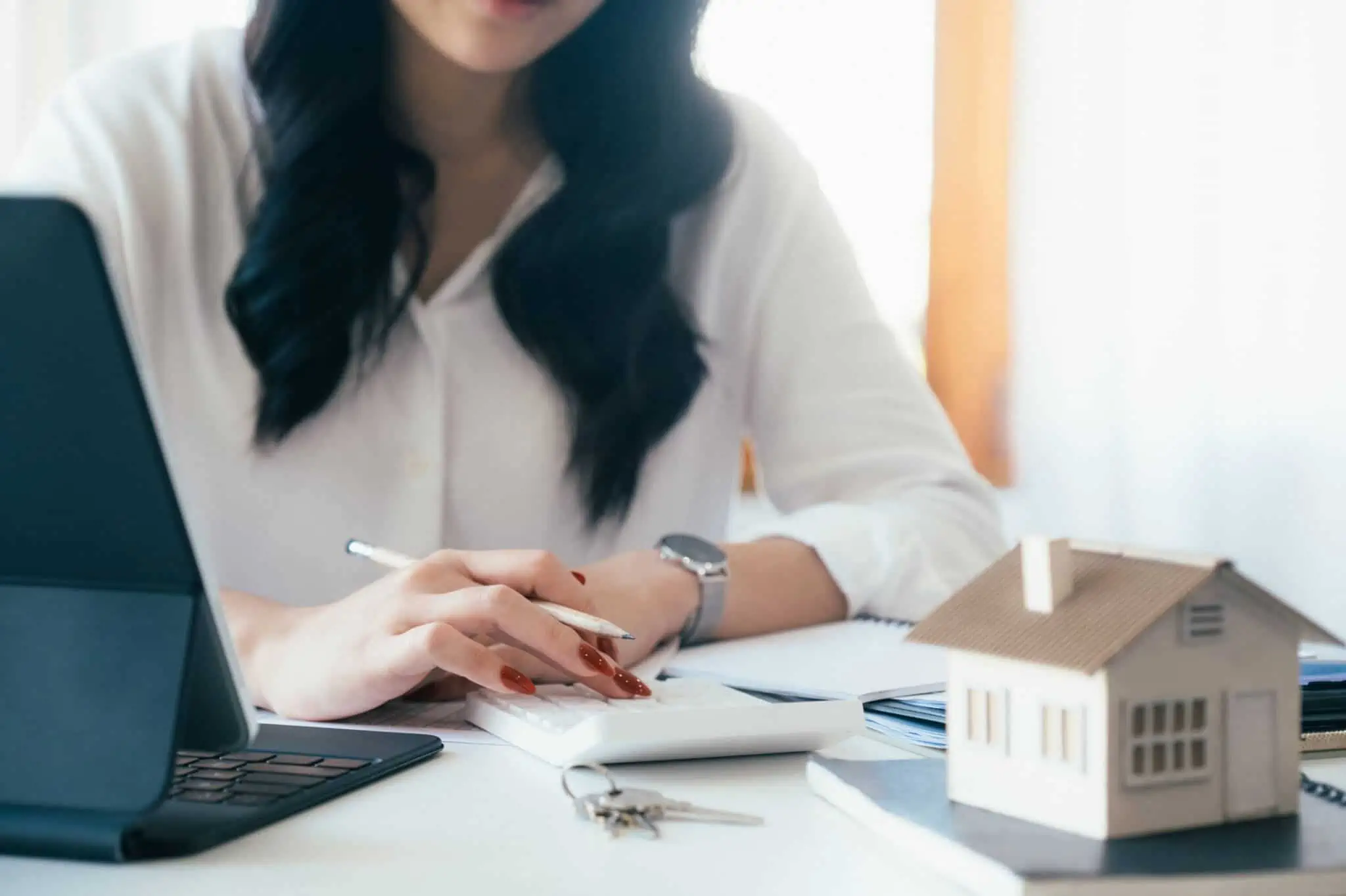 Quero vender a minha casa, como é feito o cálculo das mais-valias? mulher a fazer o cálculo das mais-valias que vai pagar após vender a sua casa
