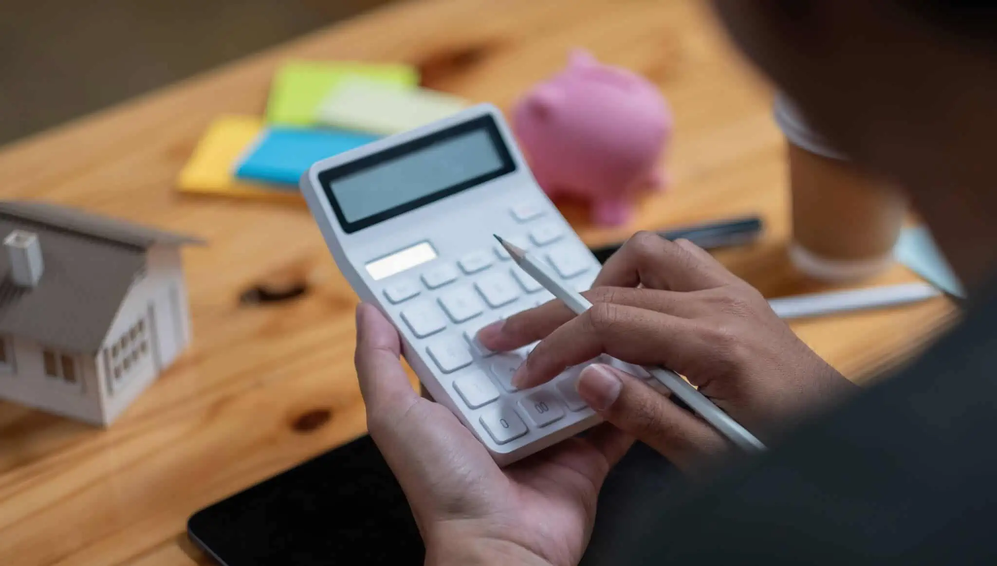 Quanto dinheiro preciso para comprar uma casa? pessoa a fazer contas numa calculadora para ter a resposta de quanto dinheiro preciso para comprar casa