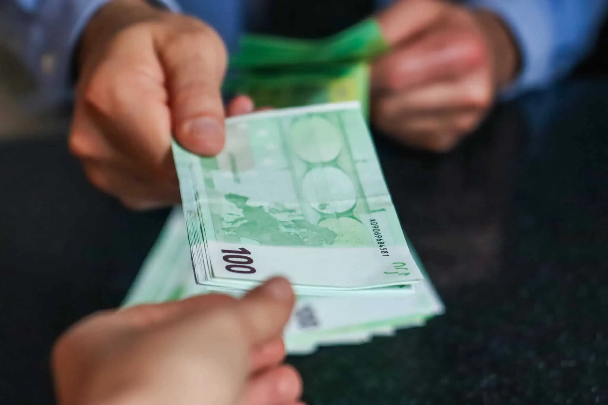 Certificados de aforro: O que muda com a nova série F? pessoa a segurar notas de 100 euros