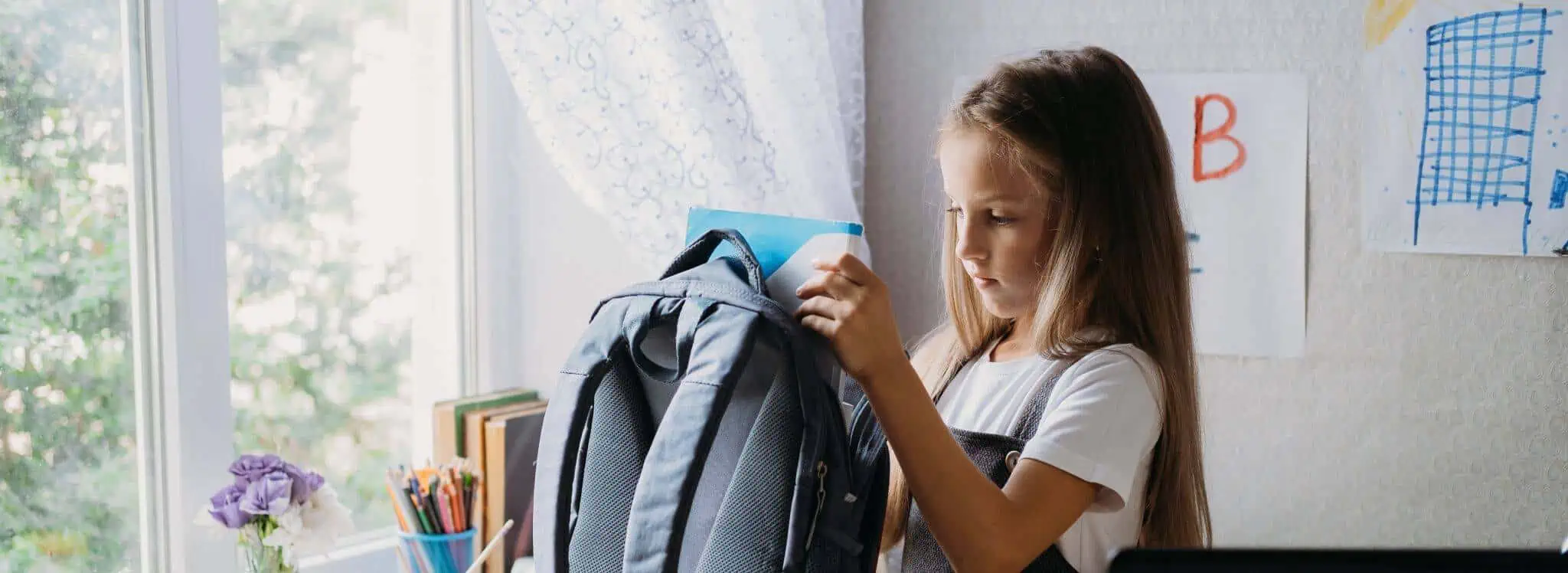 Despesas de educação: Quais são dedutíveis no IRS? rapariga no quarto a preparar a mochila para as aulas