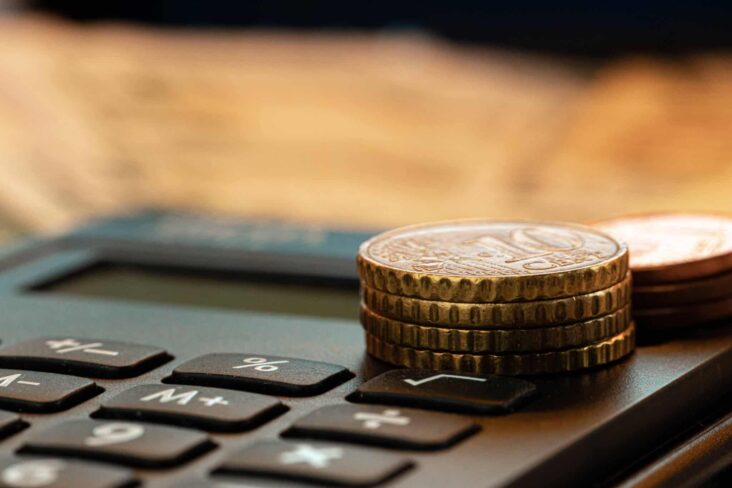 calculadora com pequena pilha de moedas ilustra pagamento de impostos em prestações