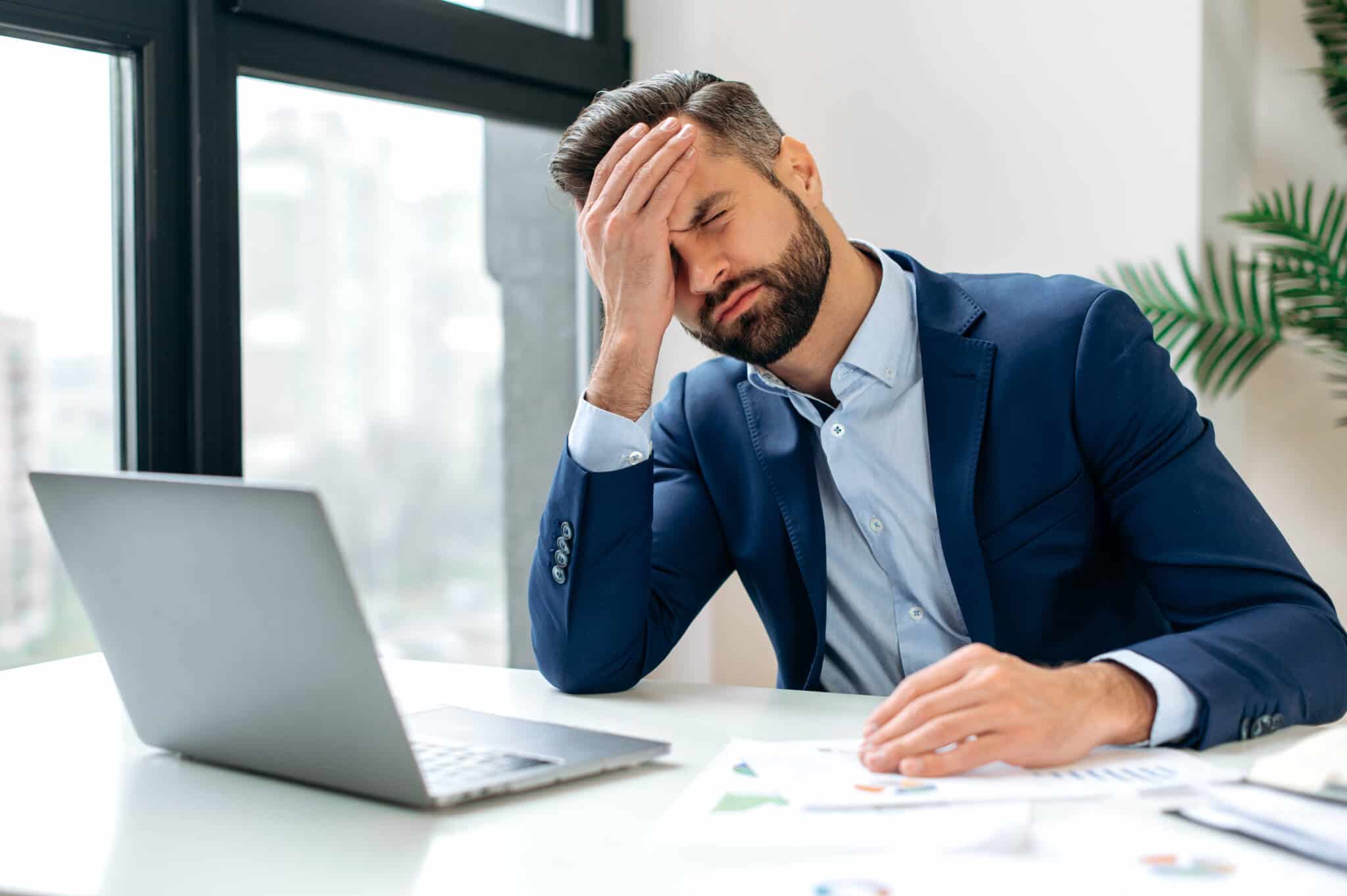 O que é a taxa de ansiedade? homem com uma taxa de ansiedade elevada a analisar as suas finanças frente ao computador