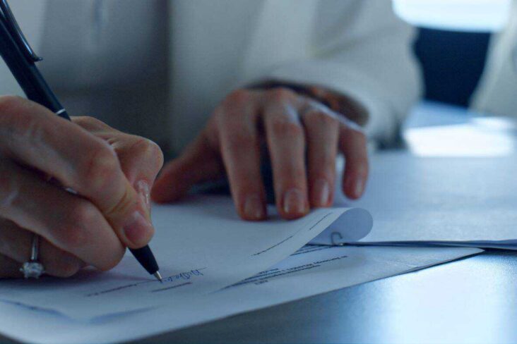 mulher com uma caneta não mão a assinar um contrato de mediação imobiliária