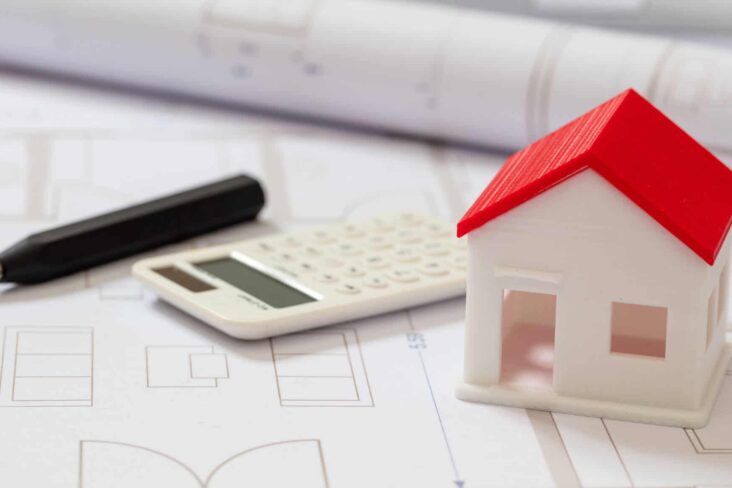 Calculadora e uma casa em cima da mesa a ilustrar os casos em que pode existir a Isenção e descontos no IMI em 2020